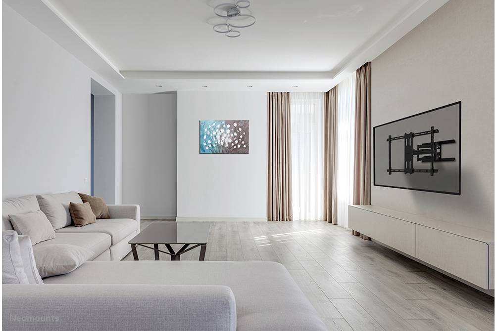 Modernes Wohnzimmer mit grauem Sofa, Glastisch, Wandbild, hellen Vorhängen und TV-Halterung an der Wand. Helle und geräumige Atmosphäre.