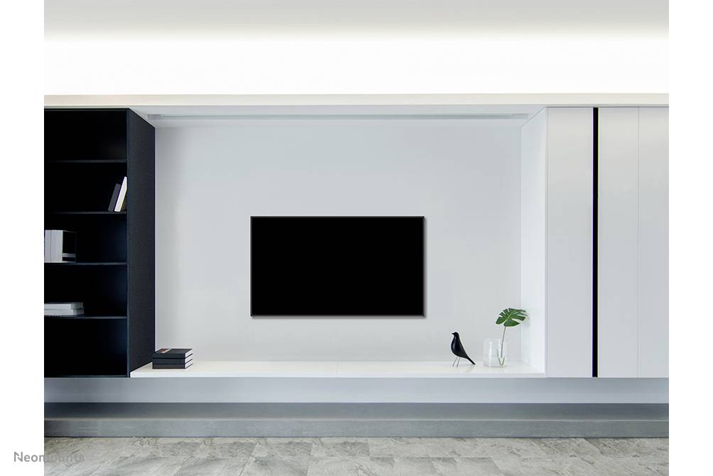 Minimalistisches Wohnzimmer mit Wandregal, Fernseher, und Dekoration; darauf ein Vogel und eine Vase mit Pflanzen.