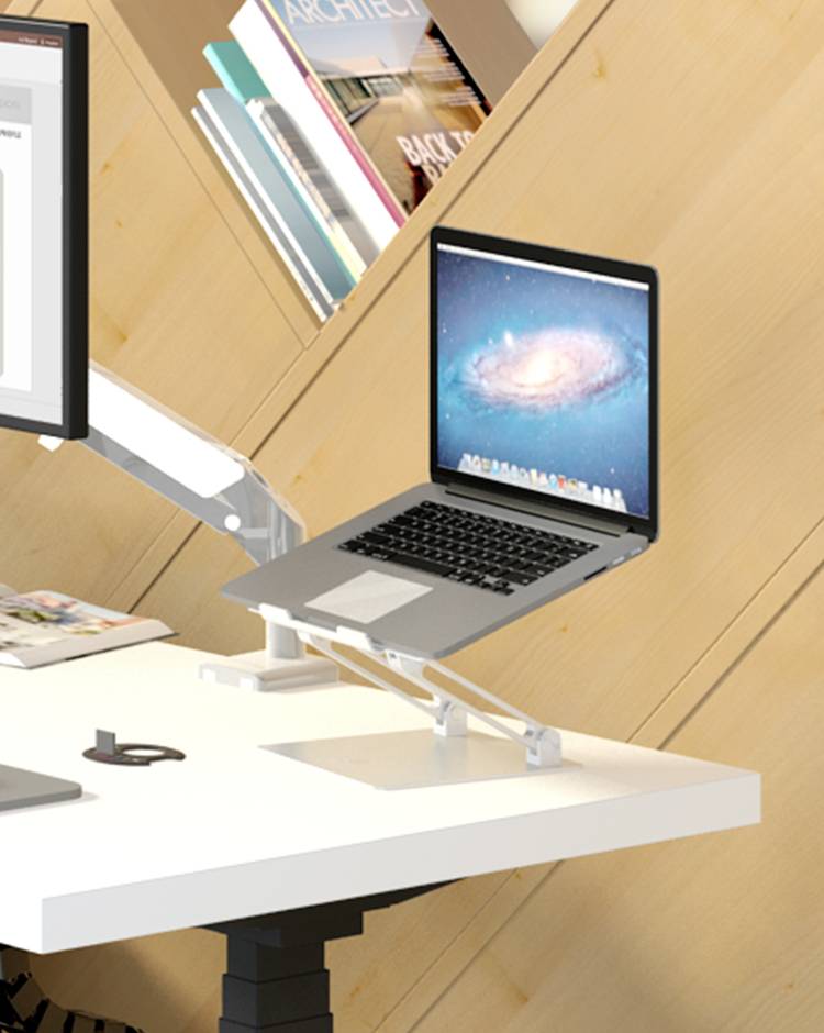 Ein Laptop auf einem verstellbaren Ständer neben einem großen Monitor auf einem weißen Schreibtisch; im Hintergrund Bücherregale.