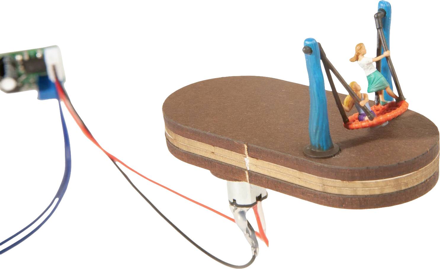 Ein kleines Holzspielzeug mit einer Schaukel, auf der zwei Modellfiguren sitzen. Kabel sind an einen Motor angeschlossen.