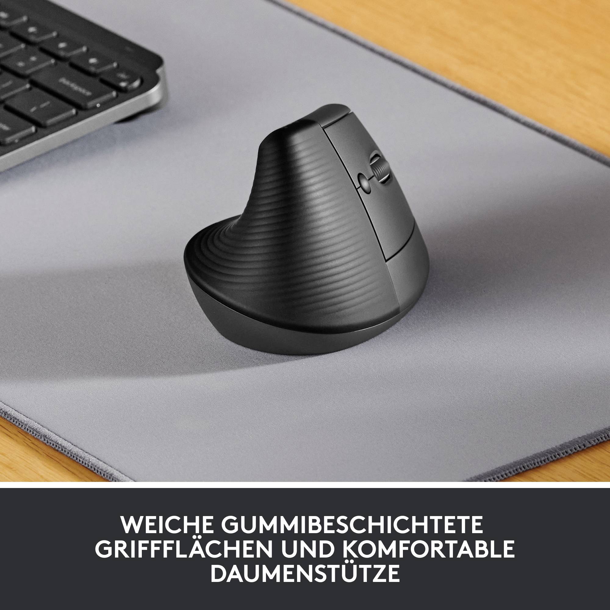 Vertikale Maus mit ergonomischem Design auf einem grauen Mousepad, neben einer Computertastatur. Text: 'Weiche gummibeschichtete Griffflächen und komfortable Daumenstütze'.