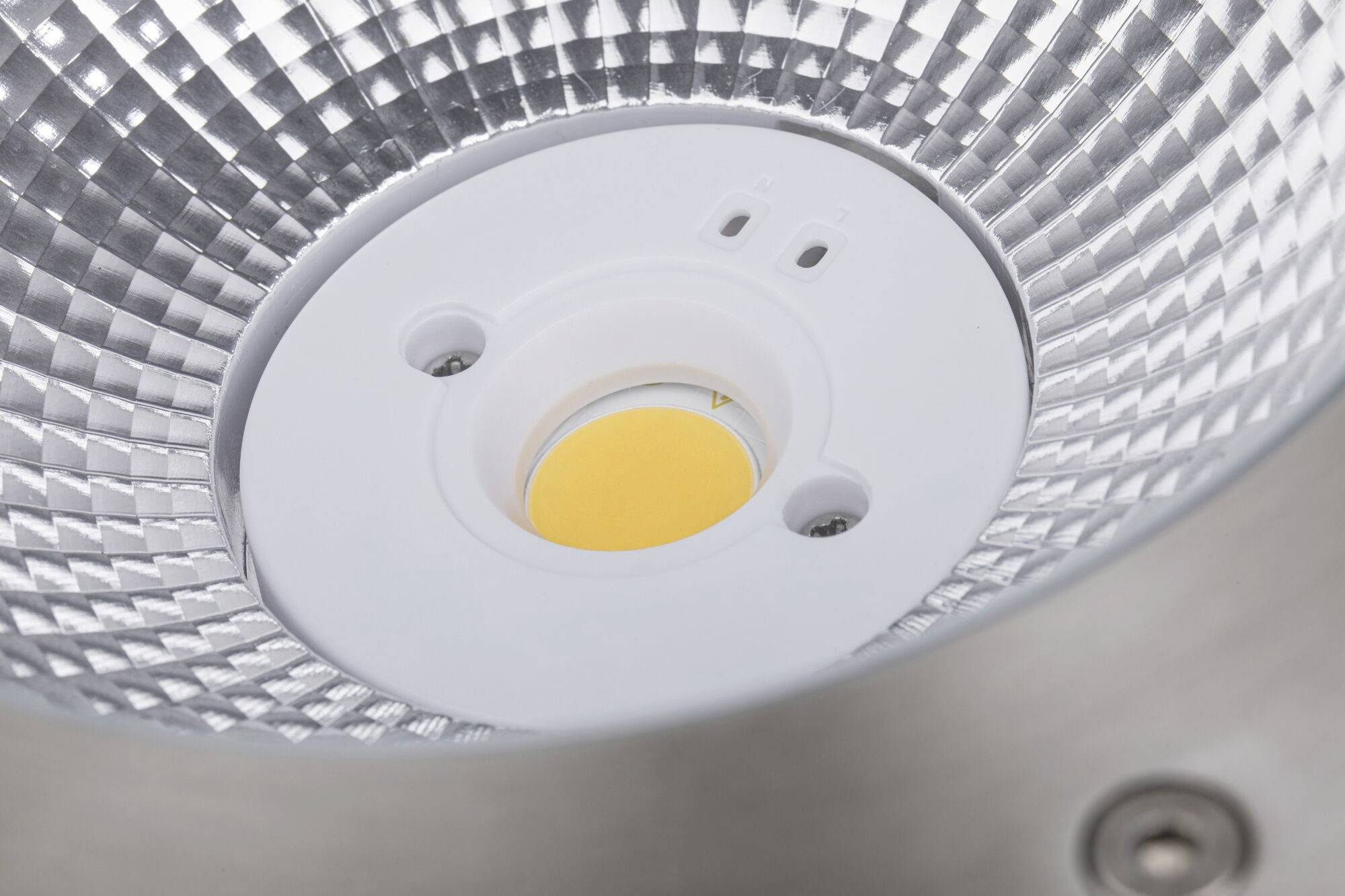 Nahaufnahme eines LED-Lichts mit reflektierendem Gehäuse und zentralem gelben Element.