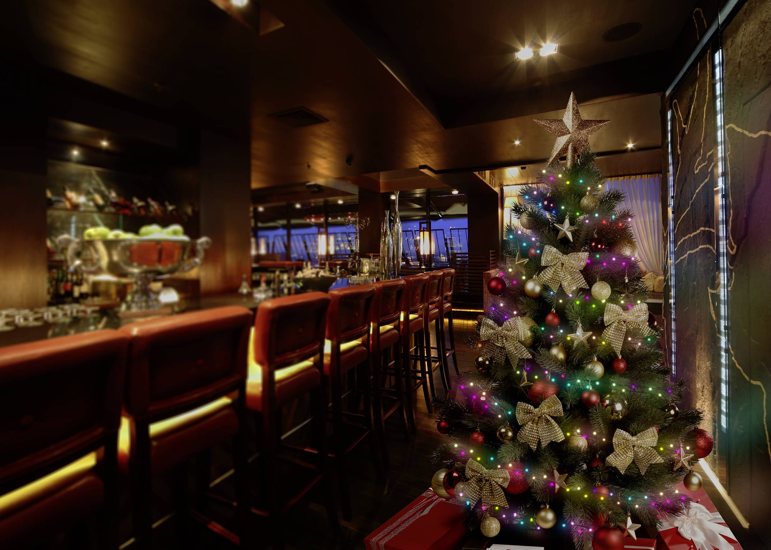 Ein festlich geschmückter Weihnachtsbaum mit bunten Lichtern steht in einem stimmungsvoll beleuchteten Restaurant oder Bar.