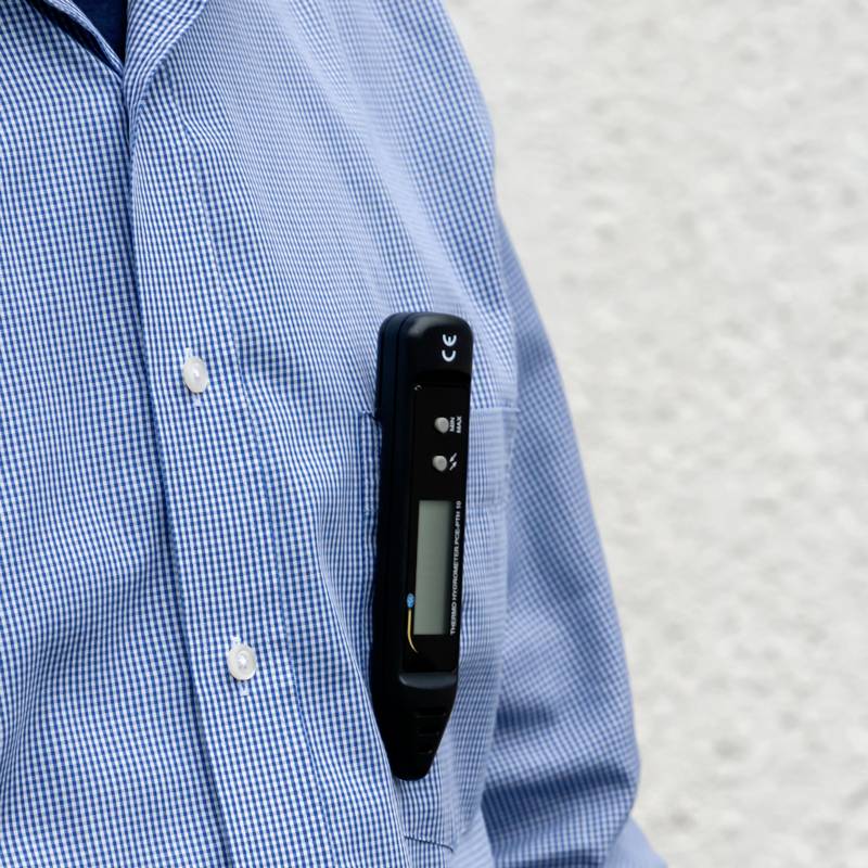 Mann im karierten Hemd hat ein schwarzes Stabthermometer in der Brusttasche.