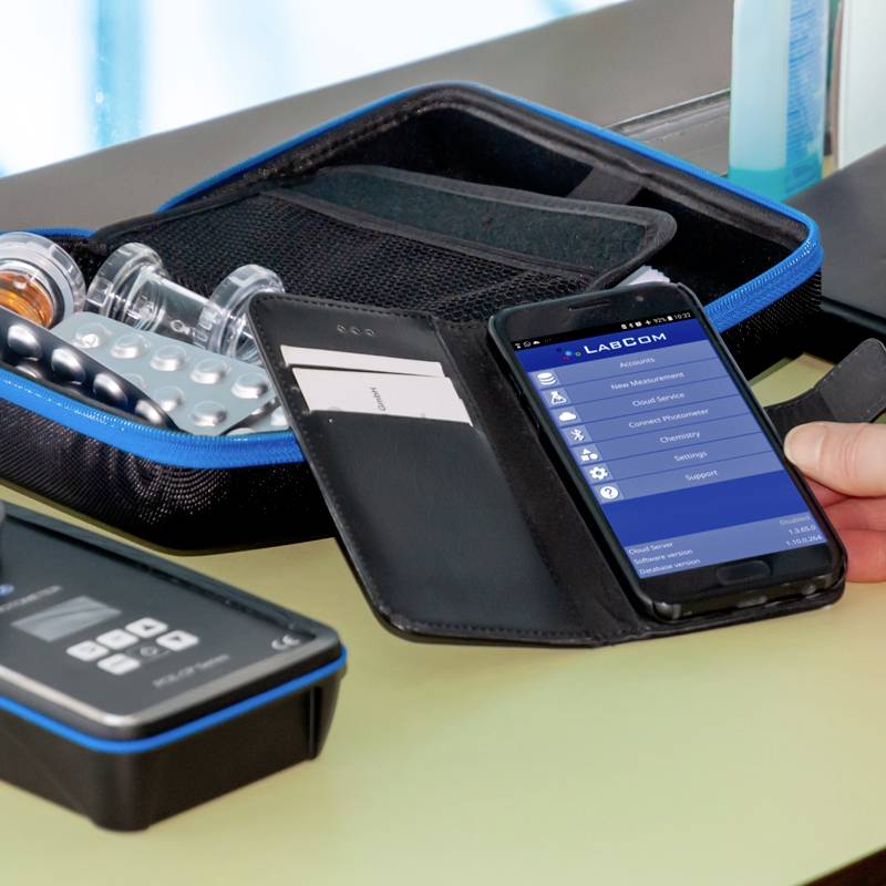 Ein Smartphone zeigt eine geöffnete App mit Optionen. Daneben liegen ein Etui mit Tabletten und zwei Fläschchen.