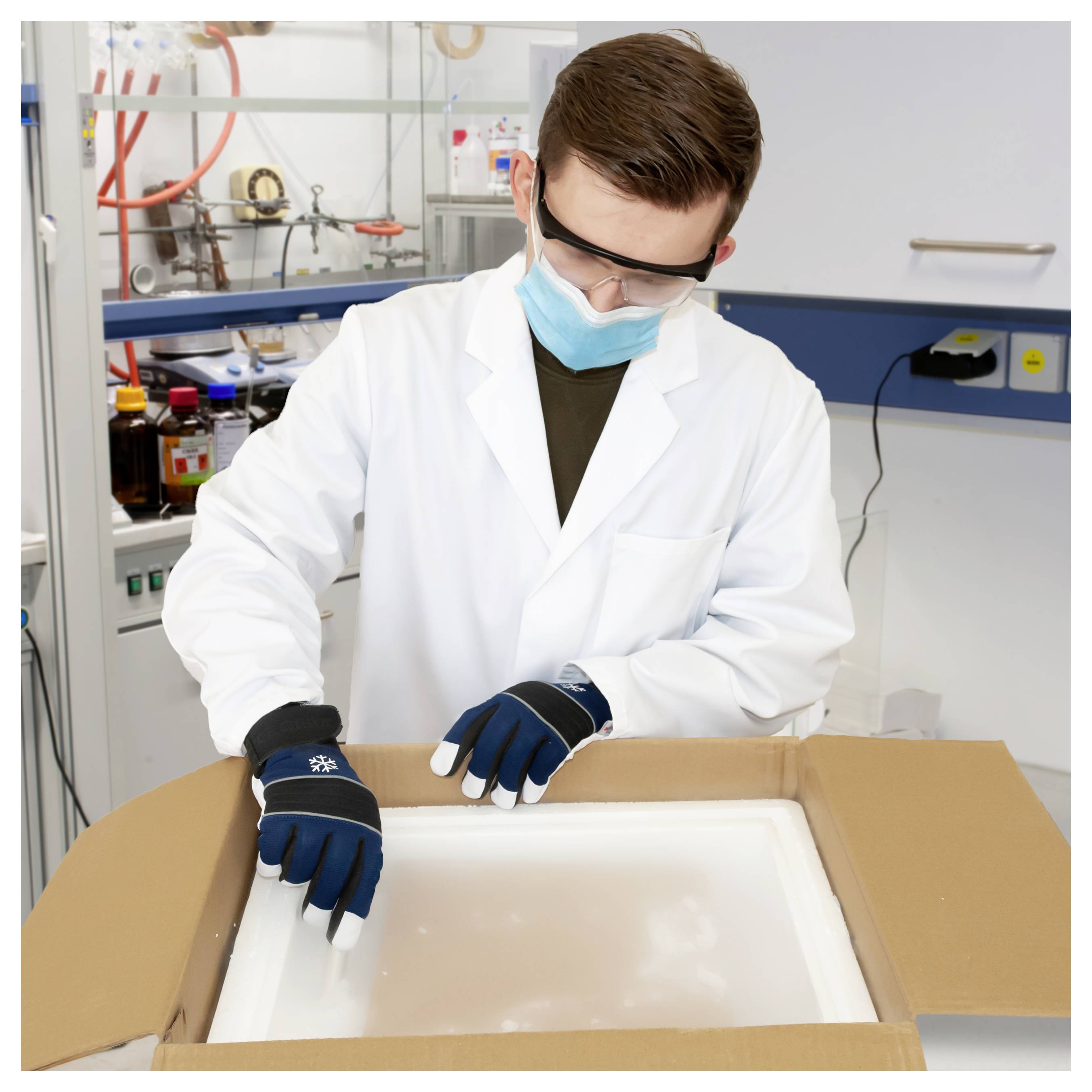 Wissenschaftler in einem Laborkittel und Handschuhen, der eine isolierte Versandbox in einem Labor öffnet.