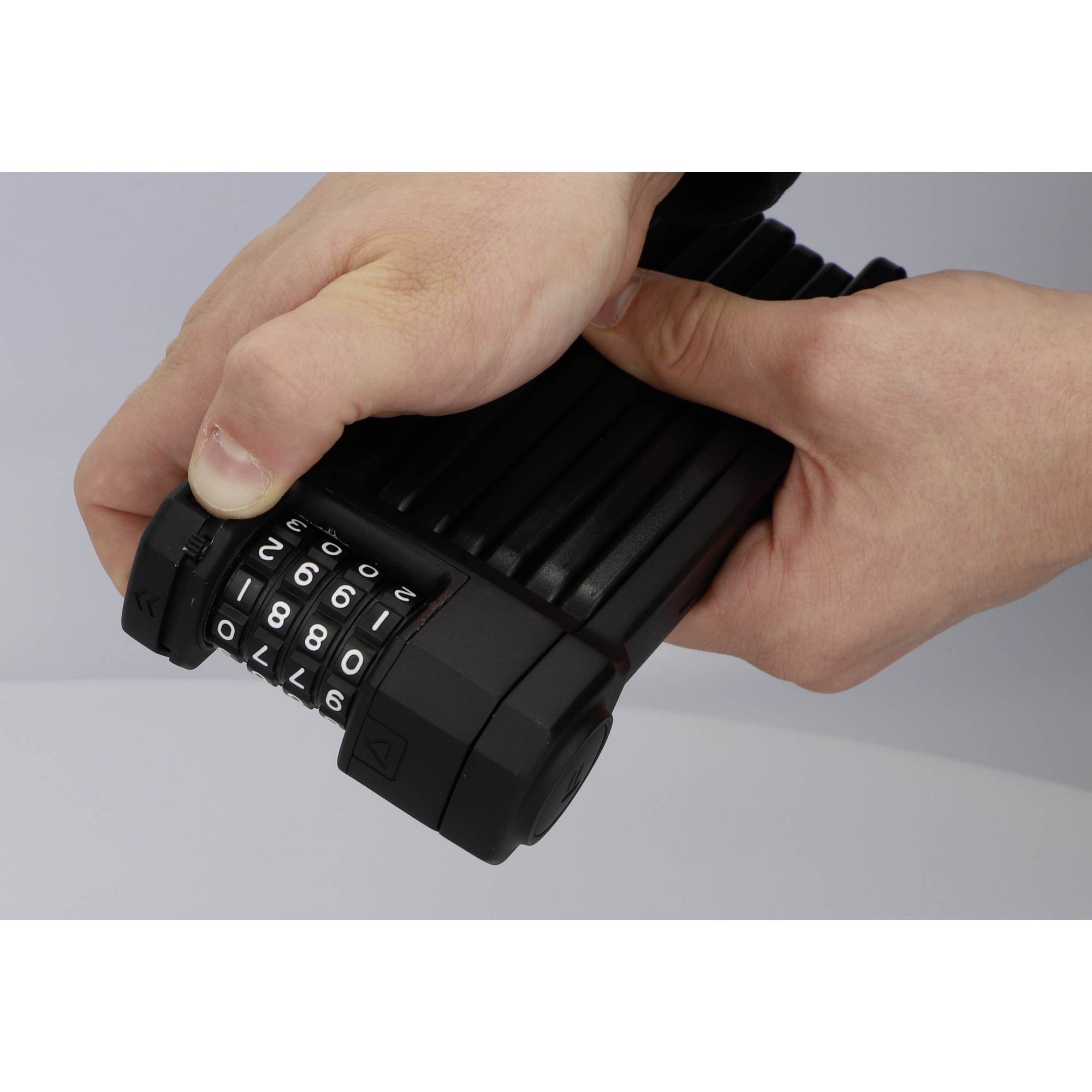 Eine Person hält ein Zahlenschloss mit den Zahlen 1800 an einem schwarzen Fahrradschloss.