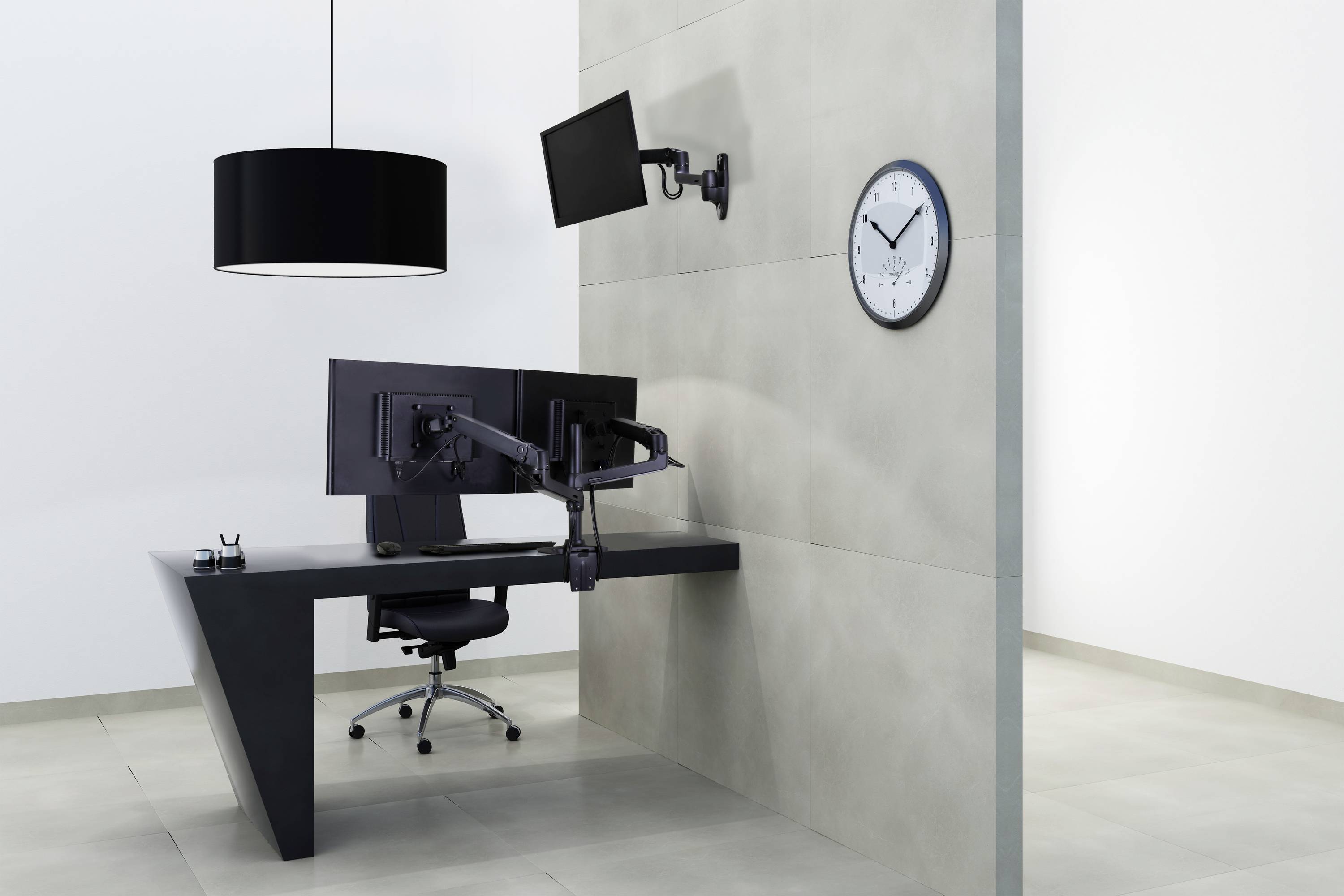 Modernes Büro mit dunklem Schreibtisch, zwei Monitoren, schwarzem Stuhl und Stehlampe. Uhr an der Wand zeigt 10:10 Uhr.
