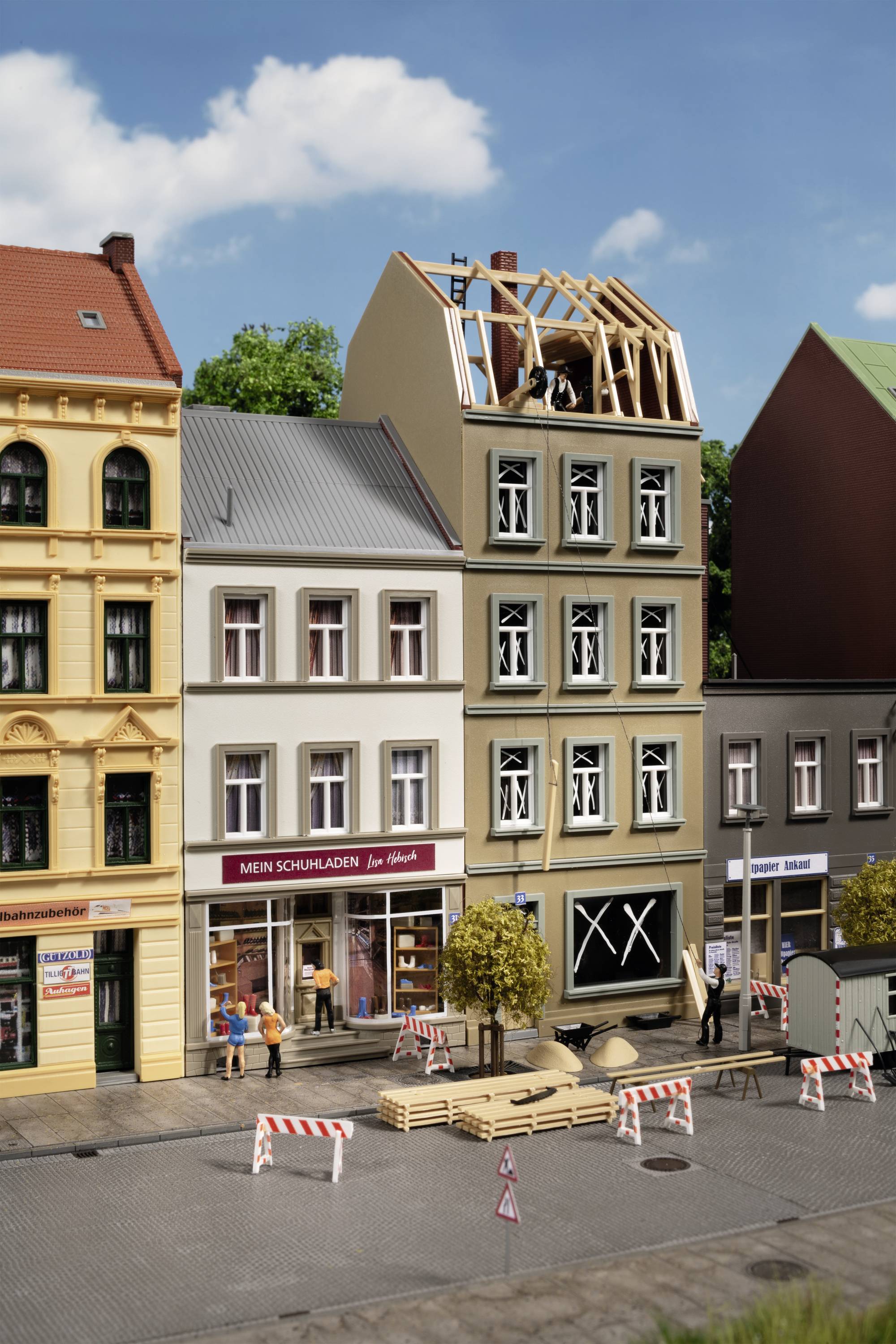 Eine Straßenszene mit Baustelle: Zwei Arbeiter reparieren das Dach eines mehrstöckigen Gebäudes. Absperrungen sichern den Bereich.