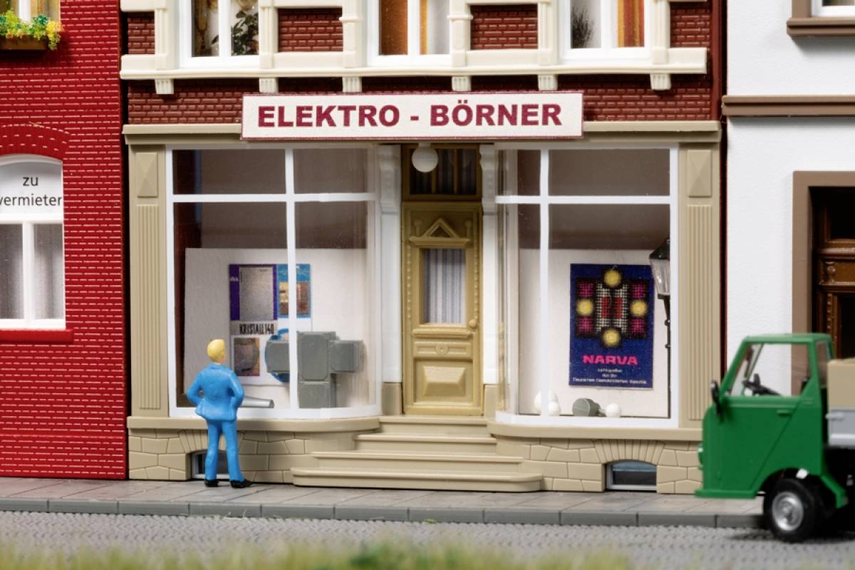Ein Miniaturmodell eines Elektrogeschäfts mit dem Schild 'ELEKTRO - BÖRNER'. Ein Mensch steht davor, ein grünes Auto ist rechts.