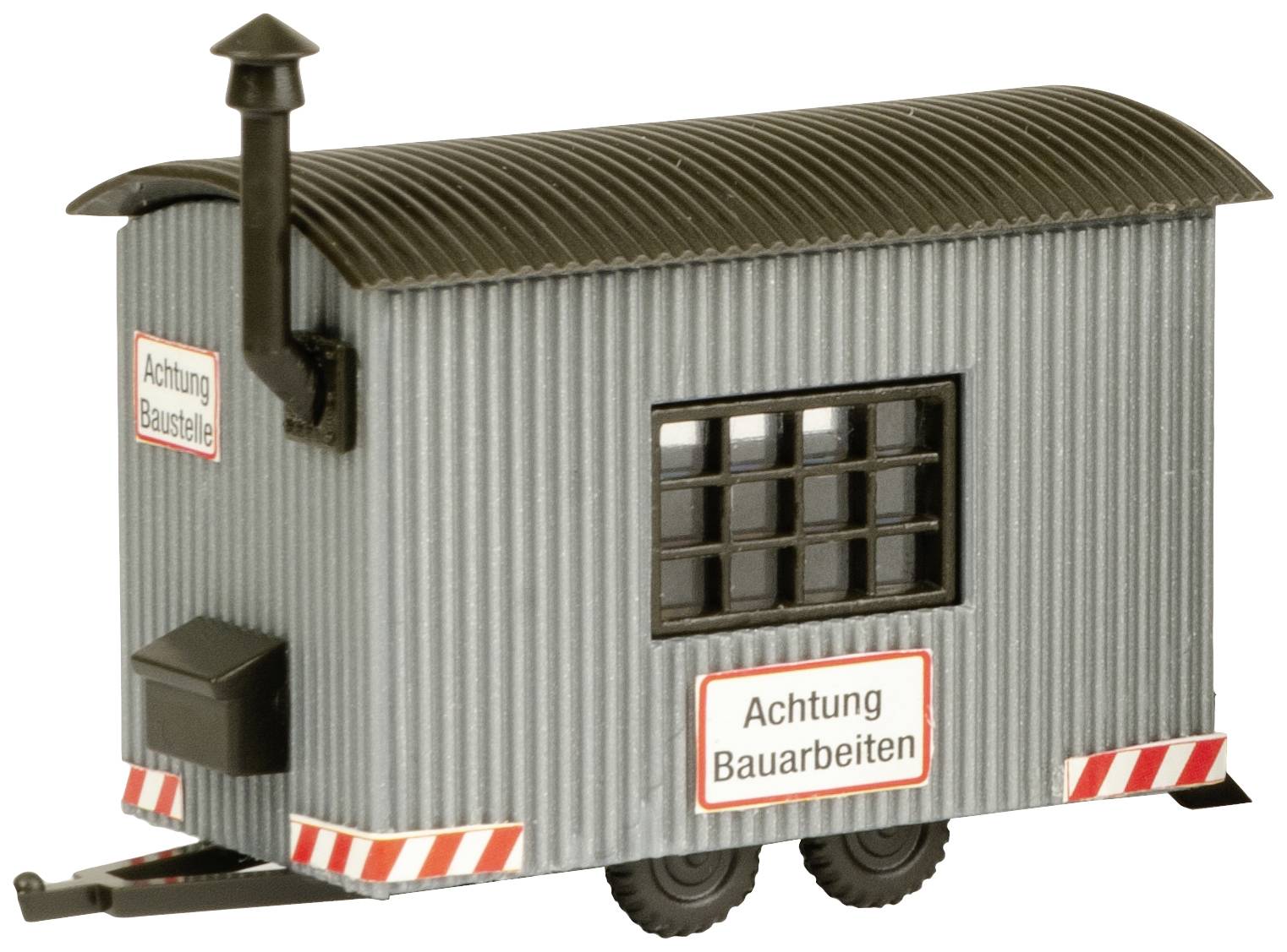 Ein grauer, mobiler Baucontainer mit dem Schild 'Achtung Baustelle' und einem Schornstein auf dem Dach, steht auf zwei Rädern.