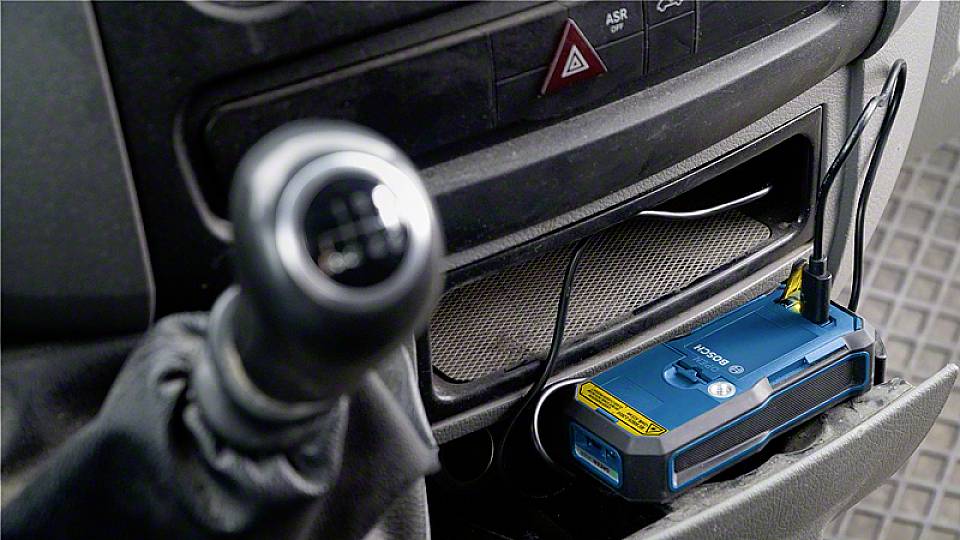Ein blaues elektronisches Gerät mit Antenne im Auto, in einem Fach unter dem Armaturenbrett neben dem Schalthebel platziert.