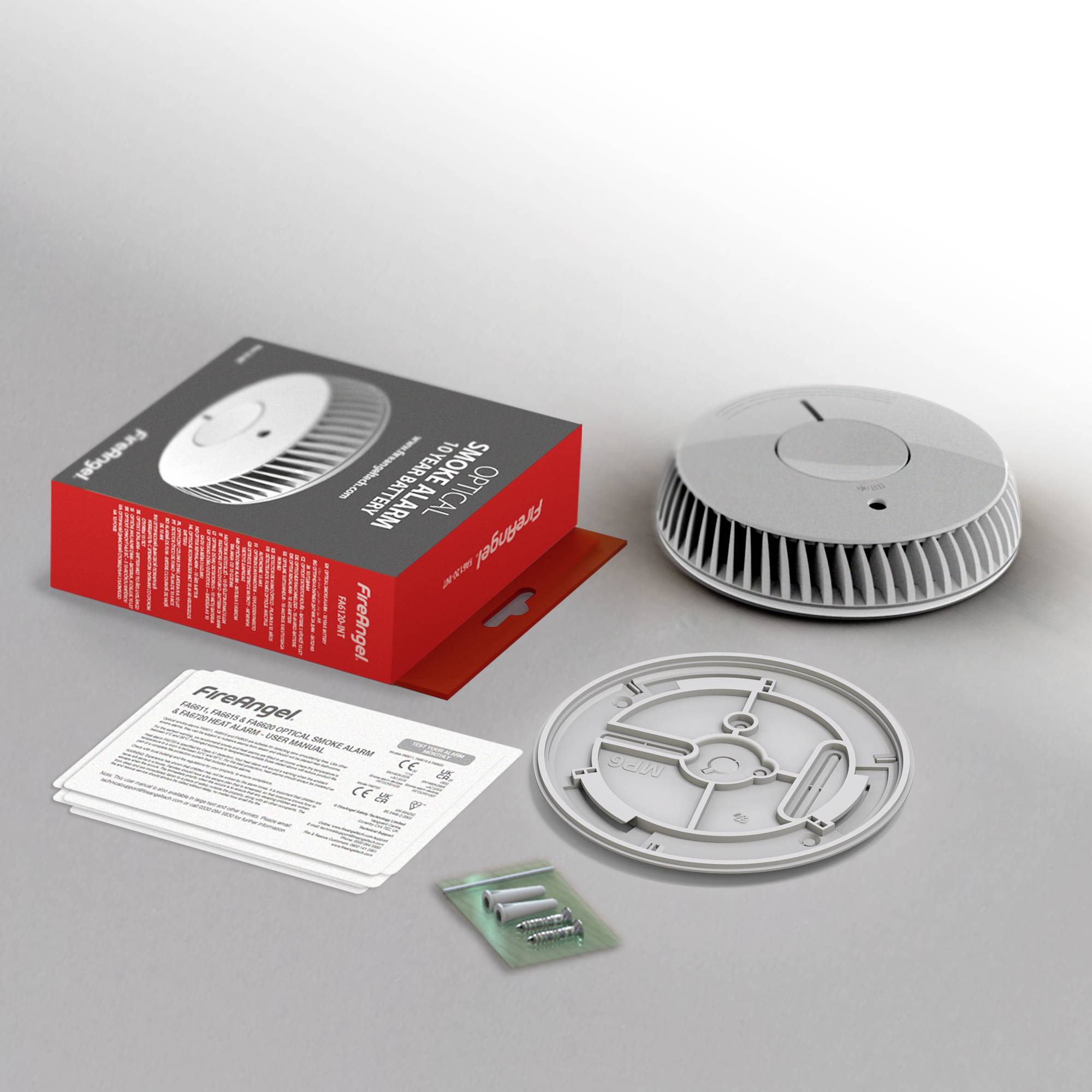 Ein Rauchmelder mit Zubehör: Verpackung, Batterien, Montageplatte und Gebrauchsanweisung sind auf einem Tisch ausgebreitet.