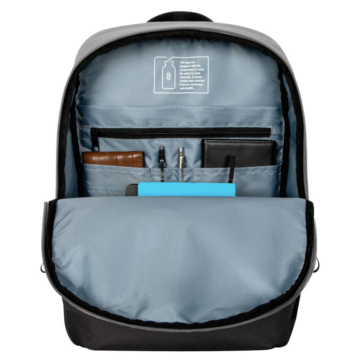 Ein geöffneter Rucksack zeigt organisiert verstaute Gegenstände, darunter ein braunes Portemonnaie, Stifte, ein Notizbuch und ein Tablet.