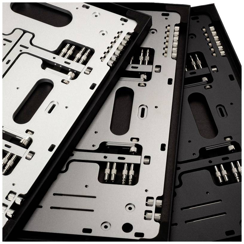 Drei leere Computergehäuse in Schwarz, Silber und Space-Grau, die nebeneinanderliegen, zeigen verschiedene Metallplatten und Schrauben.