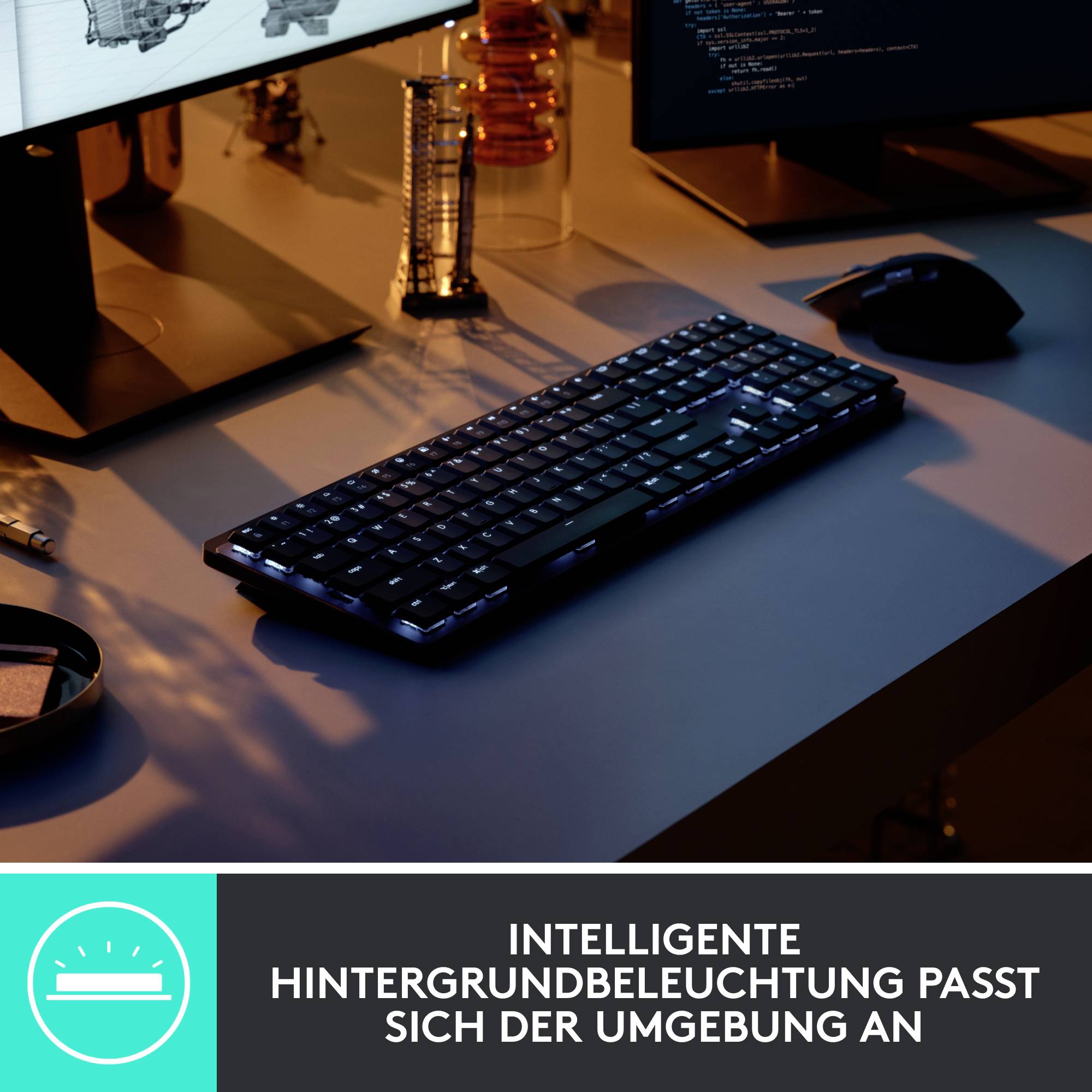 Tastatur auf einem Schreibtisch mit Monitor und Maus. Text unten: 'Intelligente Hintergrundbeleuchtung passt sich der Umgebung an.'