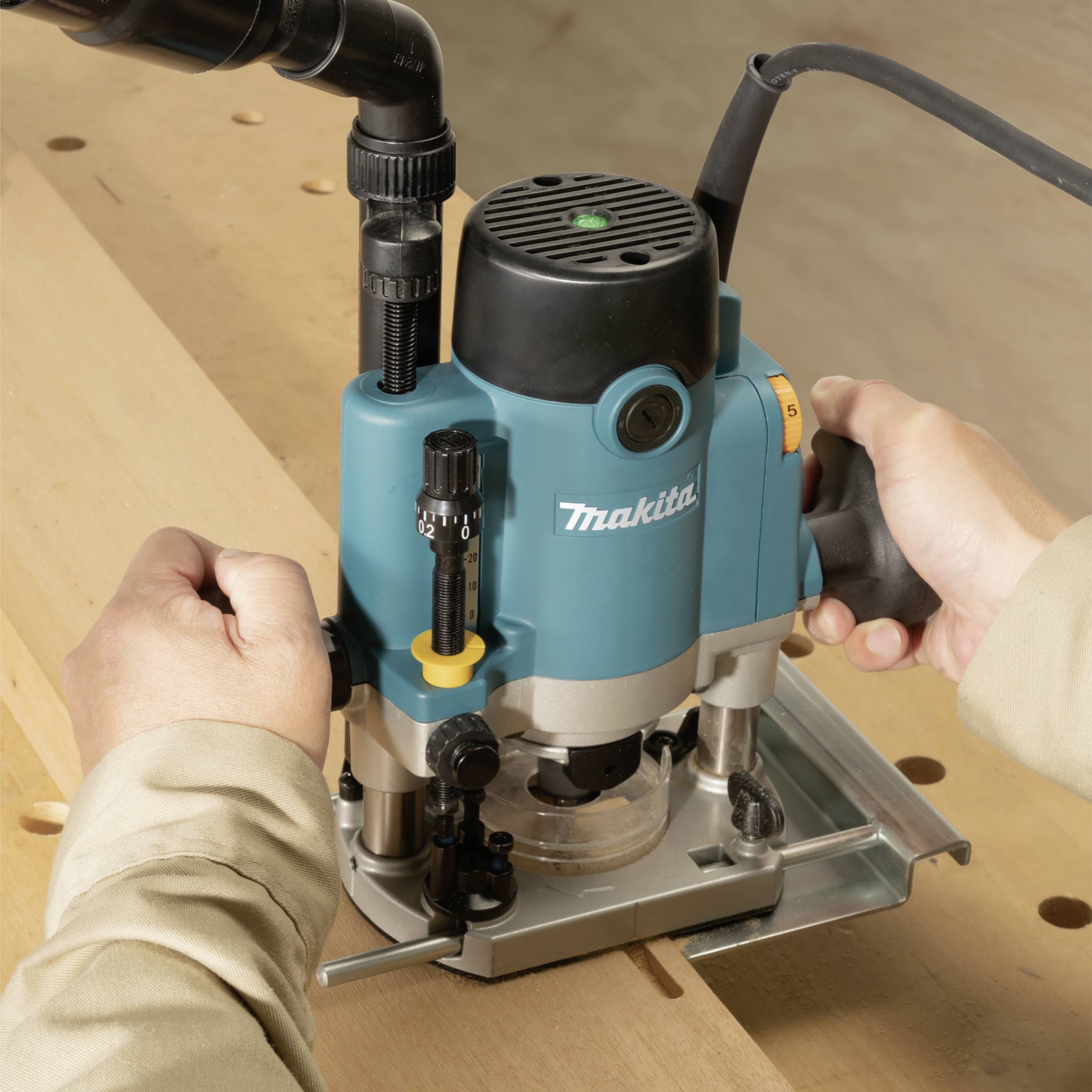 Person nutzt eine blaue Fräsmaschine auf einem Holzbrett; Fokus auf Präzisionsarbeit in der Holzbearbeitung.