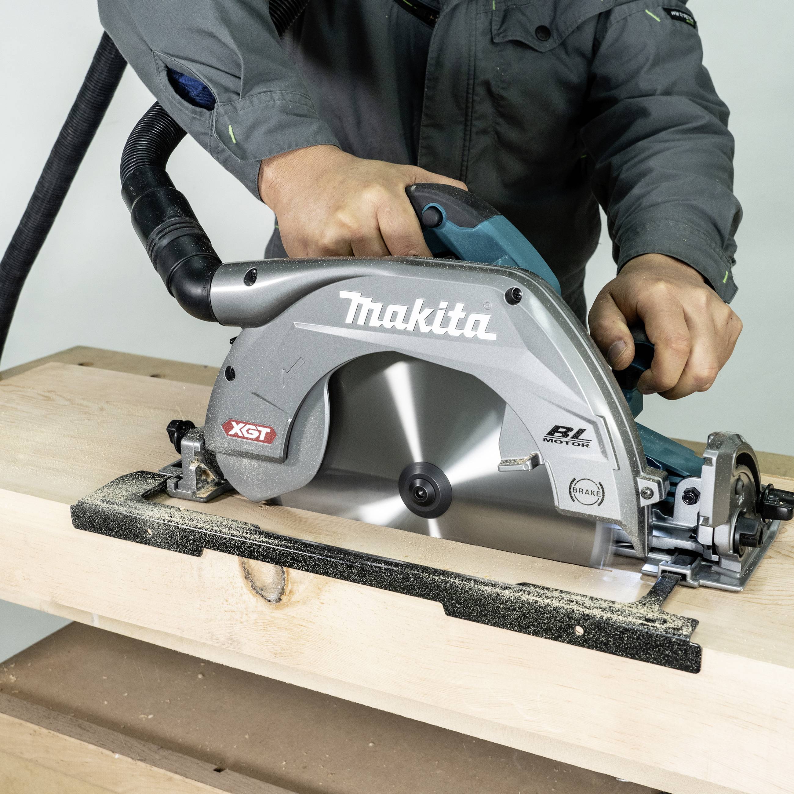 Ein Handwerker sägt mit einer elektrischen Handkreissäge durch ein Holzbrett. Die Säge erzeugt Holzspäne und Staub.