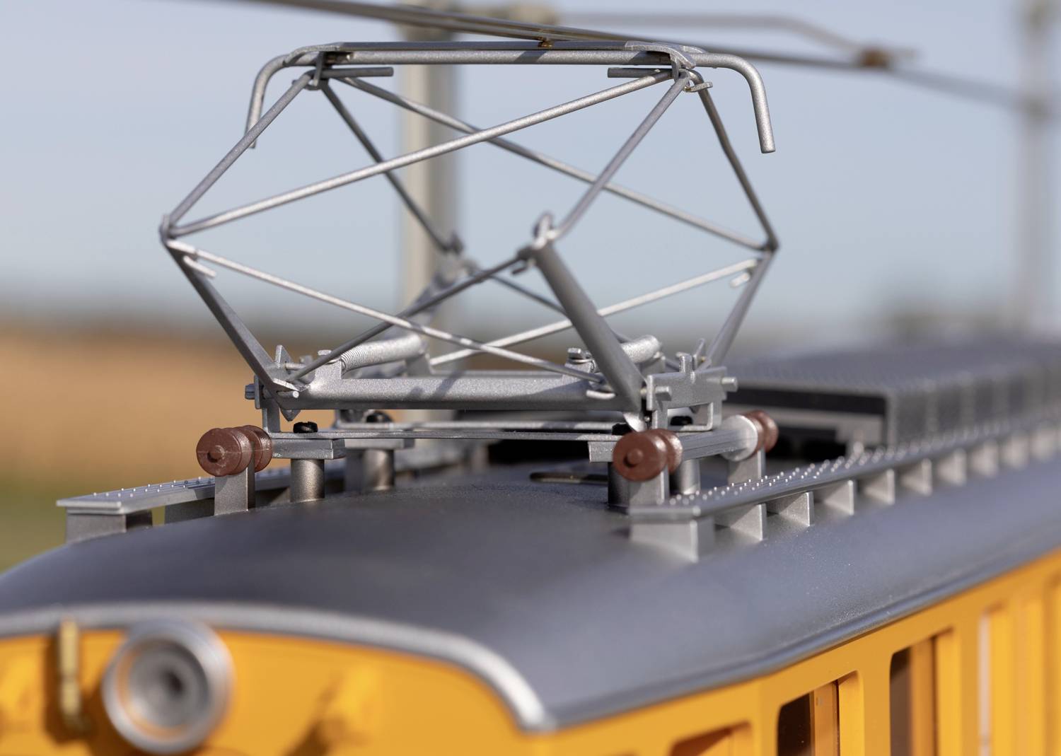 Nahaufnahme eines orangefarbenen Zugmodells mit deutlichen Details des Stromabnehmers, die Technik und Präzision des Modells hervorhebend.