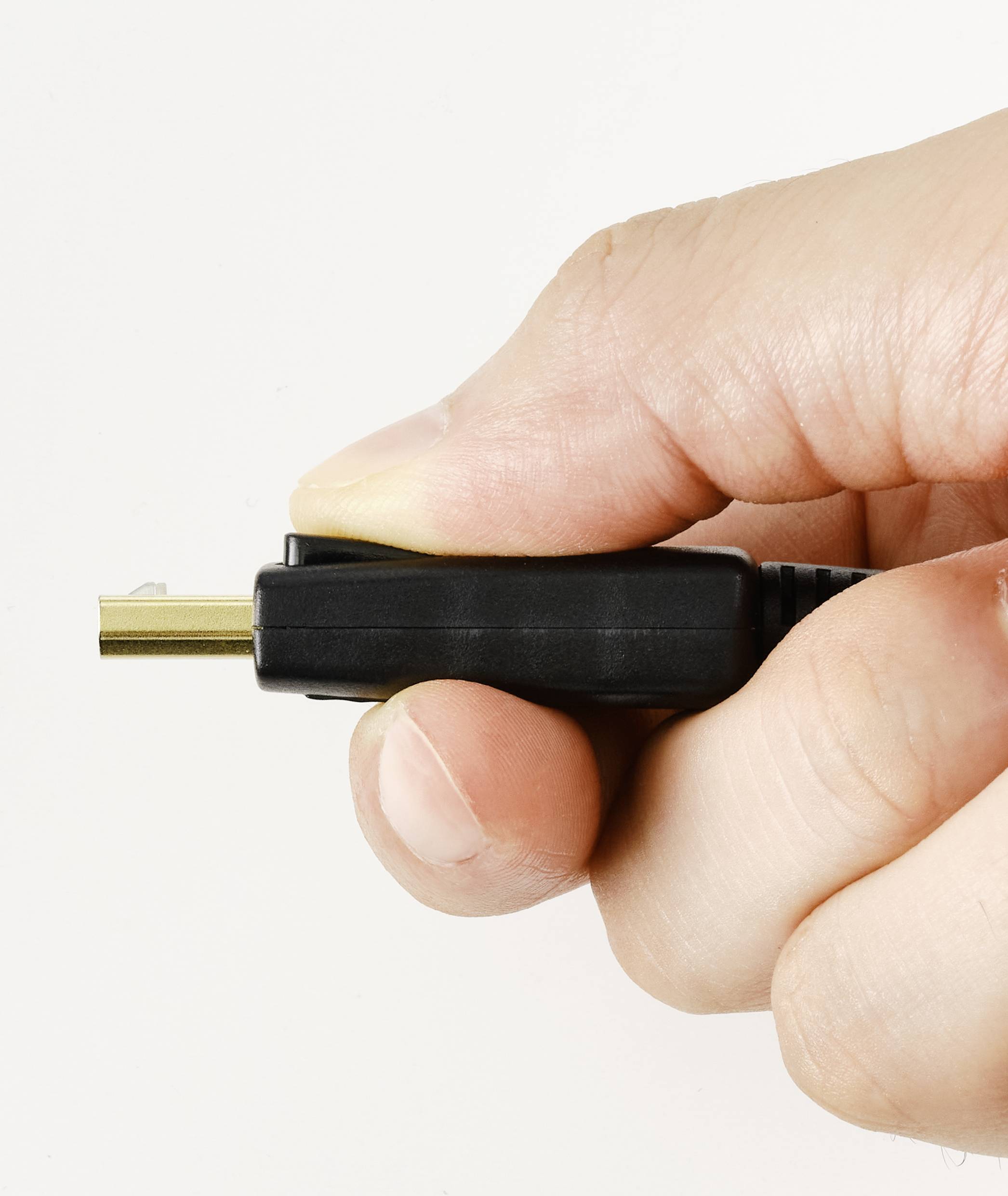 Eine Hand hält einen schwarzen Kabelstecker mit goldenen Kontaktflächen, vor einem weißen Hintergrund.