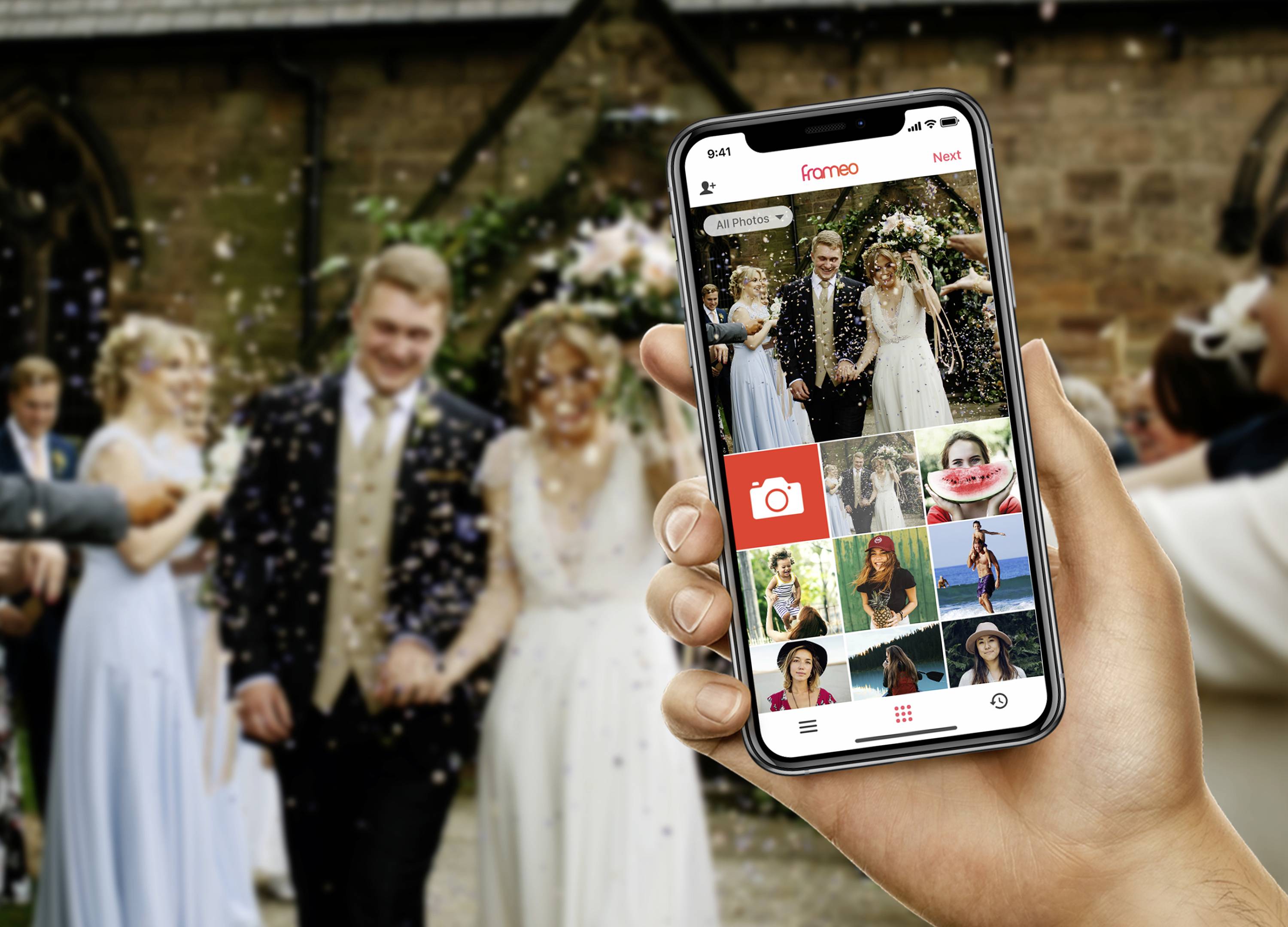 Person hält ein Smartphone mit einer Fotografie-App, im Hintergrund Hochzeitspaar und Gäste.
