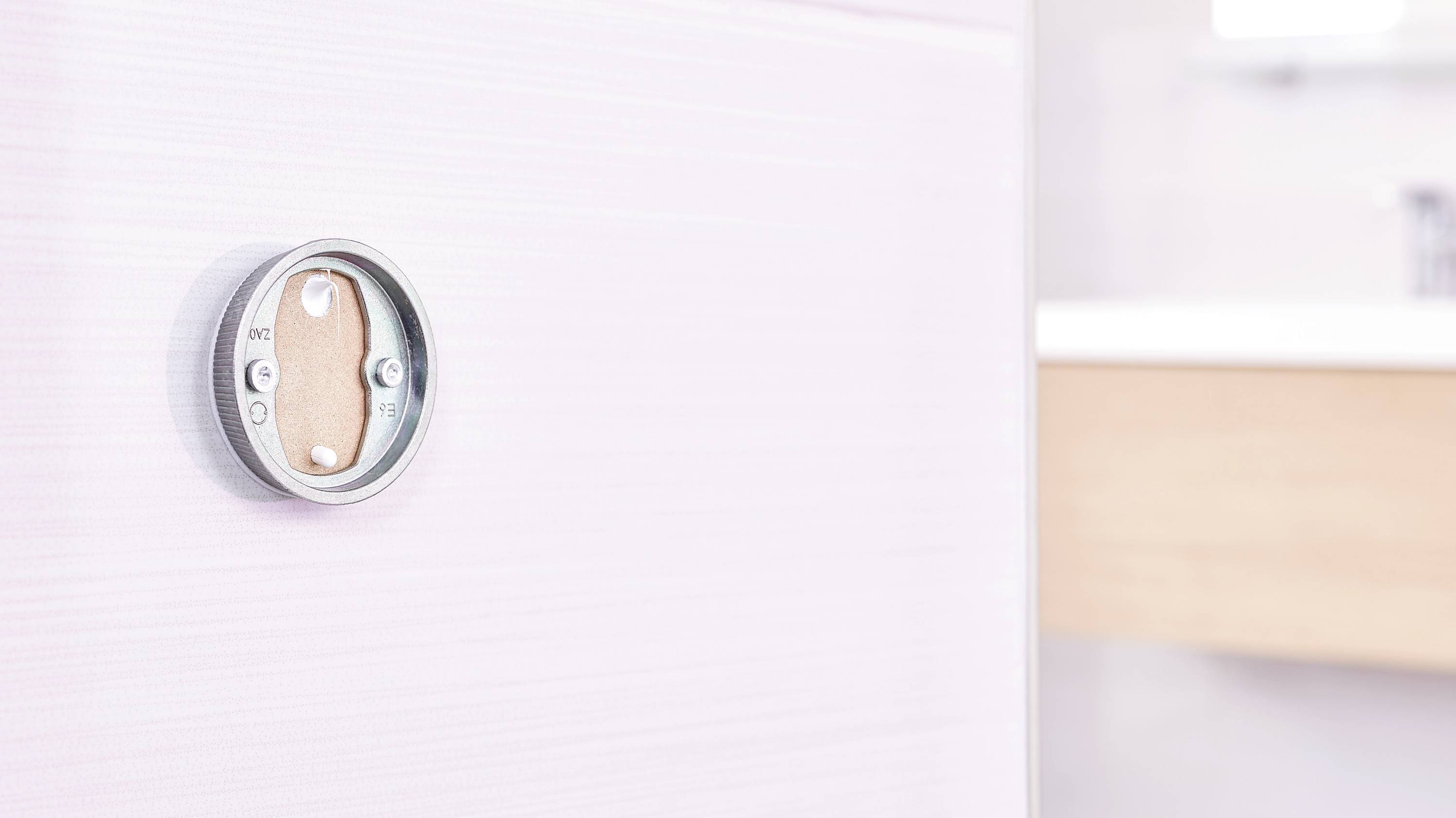 Ein rundes Thermostat an einer beigen Wand im Badezimmer. Es ist modern gestaltet und fügt sich harmonisch in die Umgebung ein.