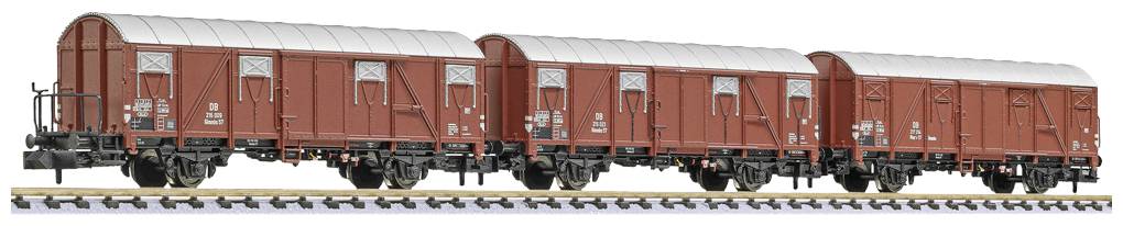 Drei rote Güterwaggons auf einem Gleis, nebeneinander gereiht, mit geschlossenen Türen und silbernen Dächern.