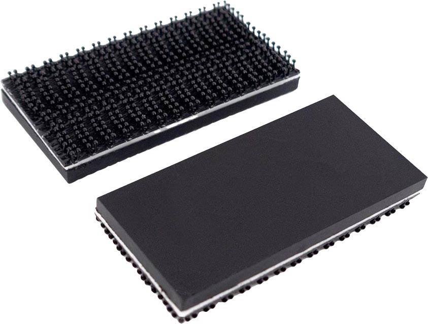 Zwei schwarze, rechteckige Objekte mit stacheligen Oberflächen, die an Klettverschlüsse erinnern. Eines zeigt die stachelige, das andere die glatte Seite.