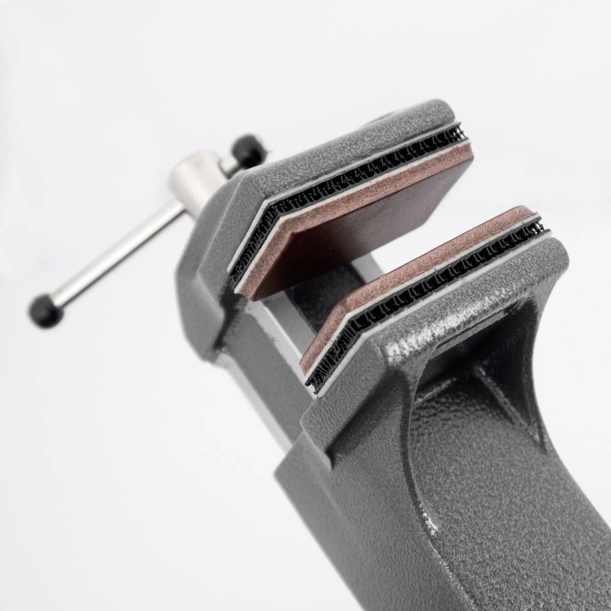 Ein Schraubstock mit großen, offenen Backen, gehalten von einer silbernen Spindel auf hellgrauem Hintergrund.