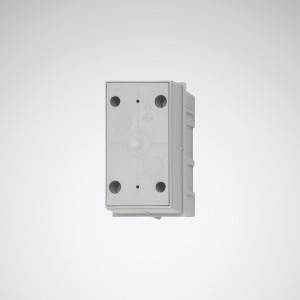 Rechteckige, graue Kunststoffdose mit mehreren kreisförmigen Ausbuchtungen und Markierungen auf der Vorderseite, gegen weiße Wand.