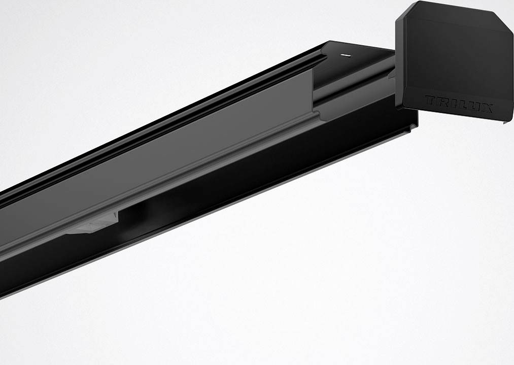 Schwarze Deckenbeleuchtung mit modernem Design, zeigt die Marke 'Trilux' auf der rechten Seite. Dezent und technisch.