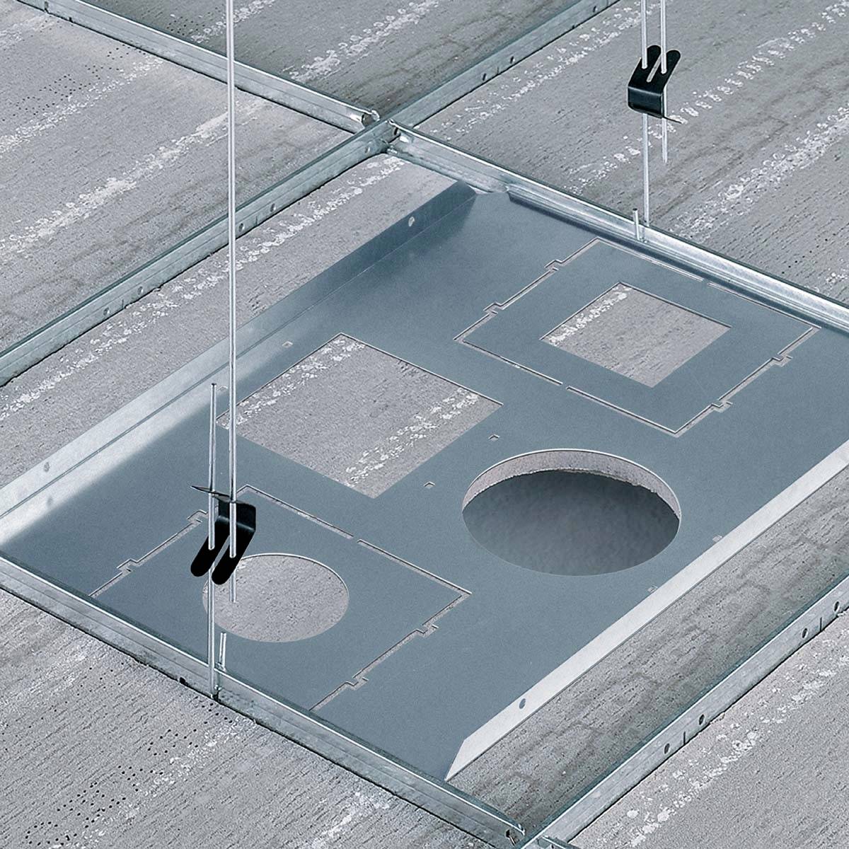 Metallschienen und -platten an einer Betondecke befestigt, mit Ausschnitten in verschiedenen Formen für Installationen oder Kabeldurchführungen.