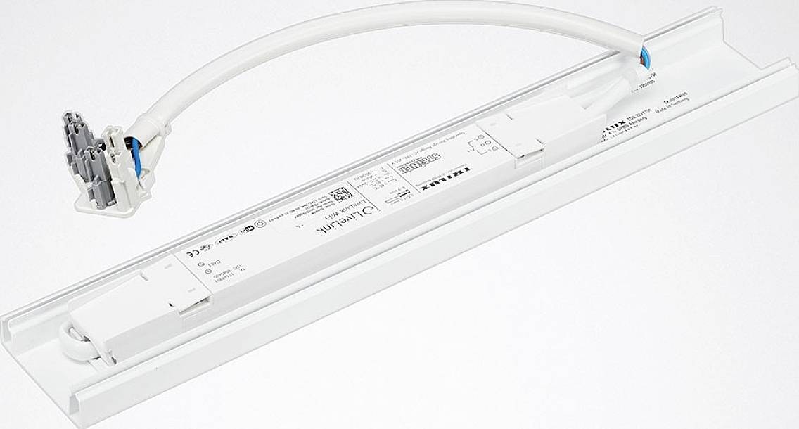 Ein LED-Treiber mit integriertem Kabel und Anschlussstück, montiert auf einer weißen Leiste. Geeignet für den Einbau in Lichtsysteme.