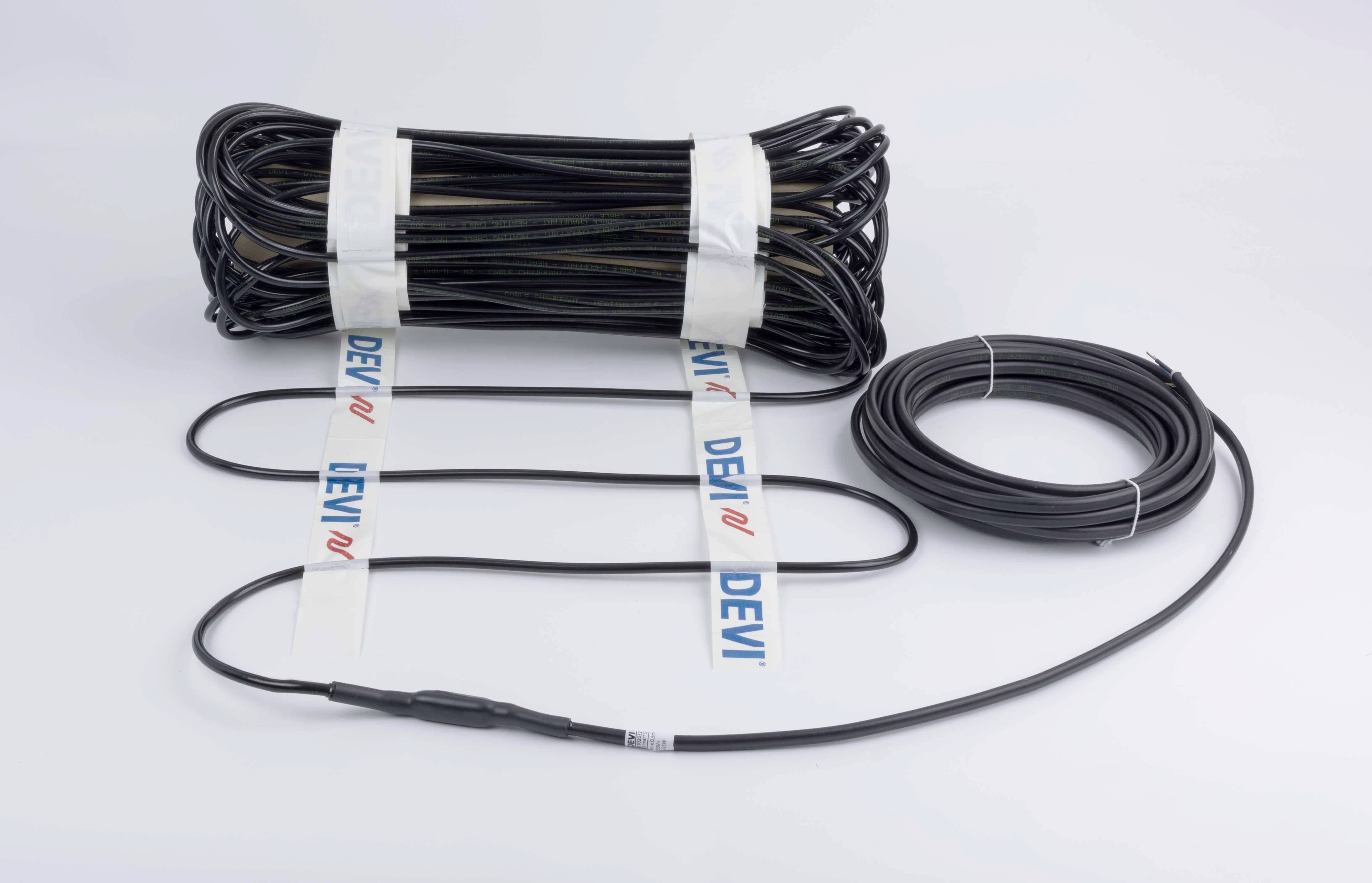 Ein elektrisches Heizkabel liegt aufgerollt auf einem Tisch. Auf dem Kabel ist das Markenlogo 'DEVI' auf weißen Bändern sichtbar.