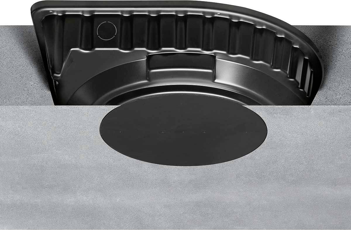 Schwarze Abdeckung in einer runden metallischen Vertiefung. Ein beschichteter Deckel liegt darauf. Industrielles Design.