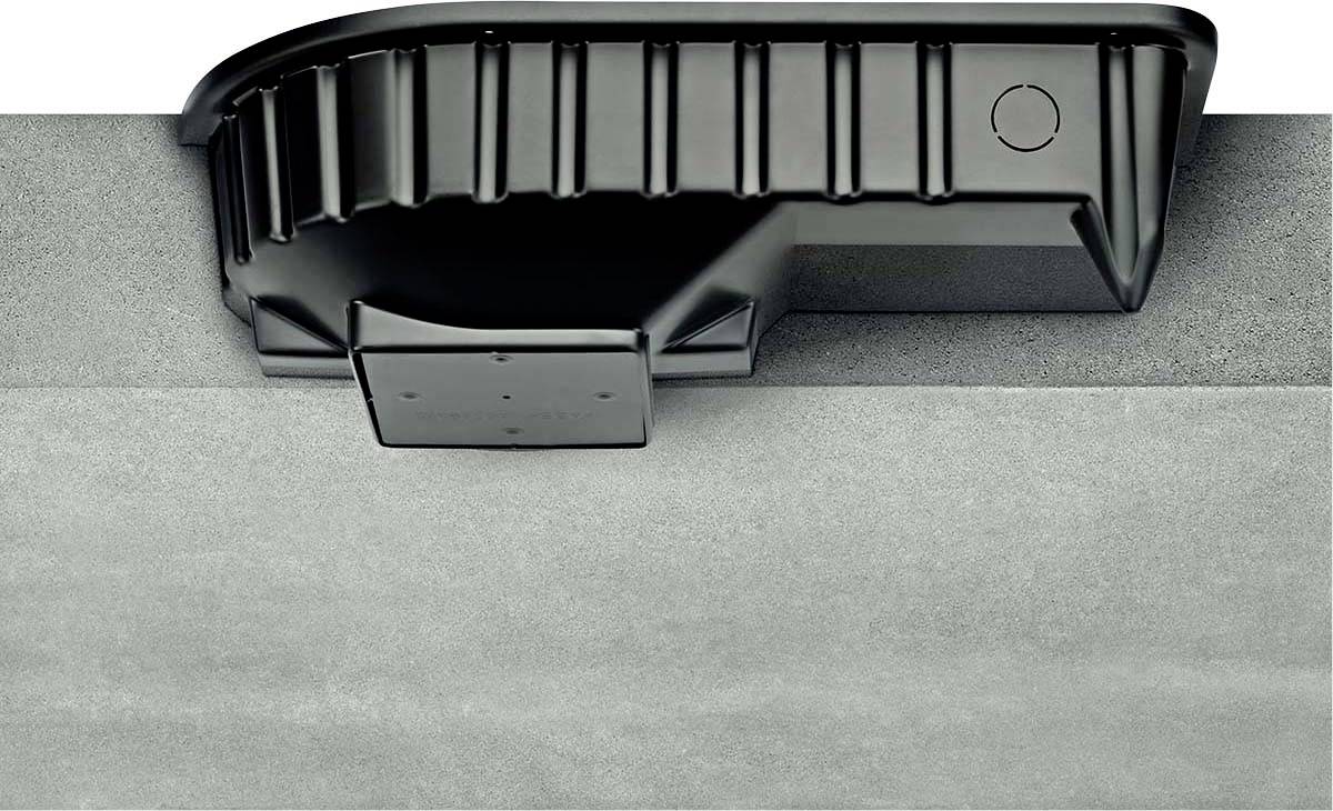 Schwarzer Kunststoffkasten auf grauer Betonfläche, evtl. Teil eines technischen Geräts, mit gerändelten Kanten und flachem Boden.