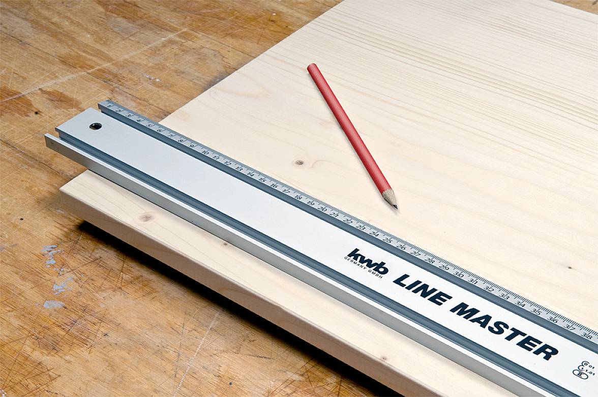 Ein Lineal und ein roter Bleistift liegen auf hellem Holz. Das Lineal trägt die Aufschrift 'LINE MASTER' und hilft beim genauen Messen.