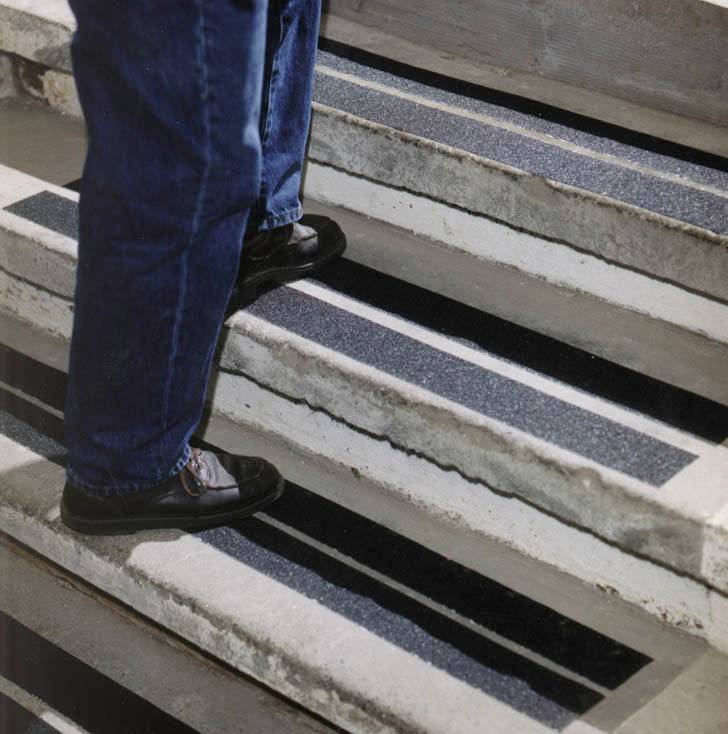 Person steigt eine Treppe hinauf, die mit rutschfesten Streifen auf den Stufen versehen ist, um die Sicherheit zu erhöhen.