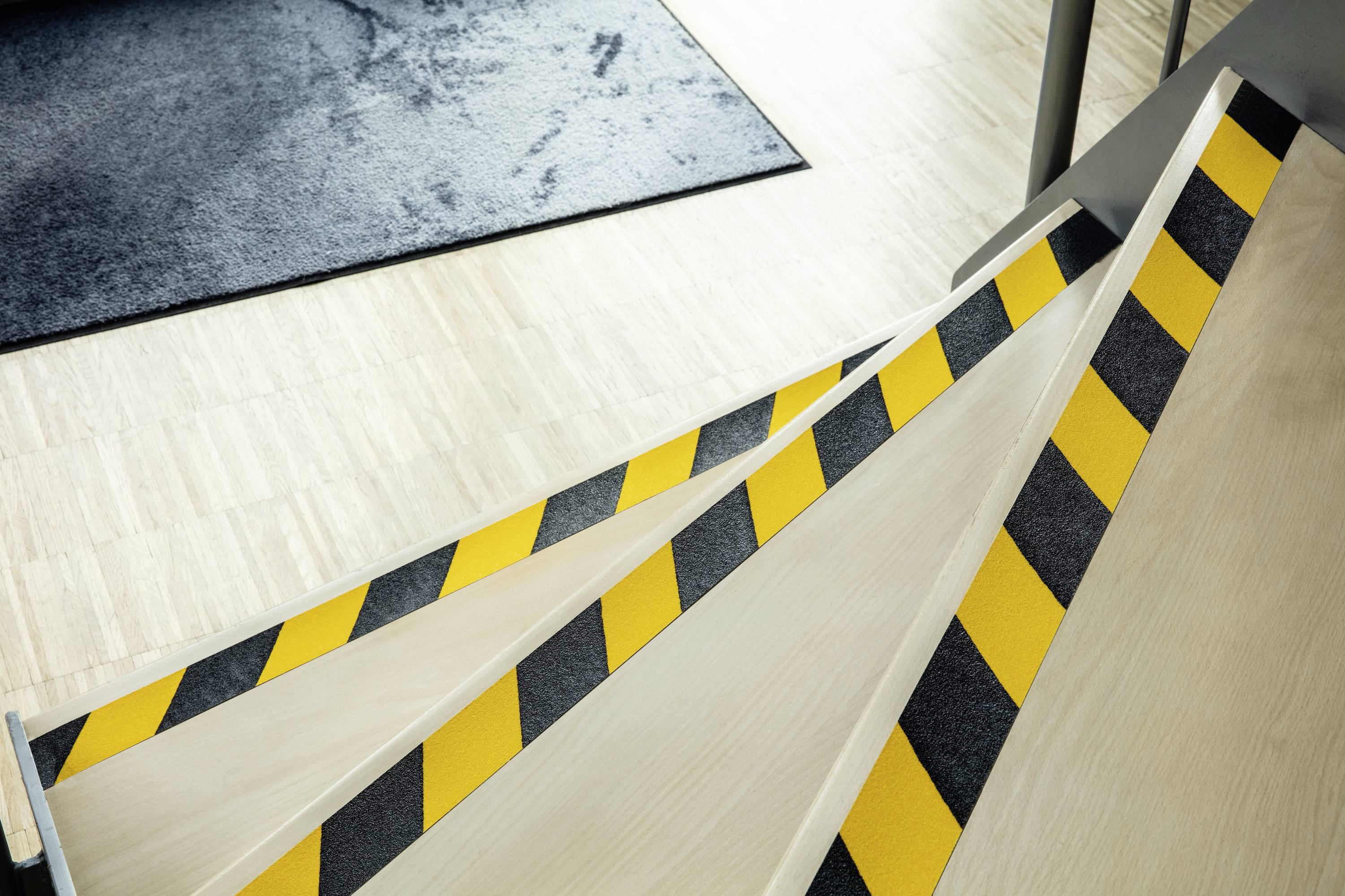 Treppe mit gelb-schwarzen Warnstreifen auf den Stufenkanten zur Erhöhung der Sichtbarkeit und Sicherheit in einem modernen Gebäude.