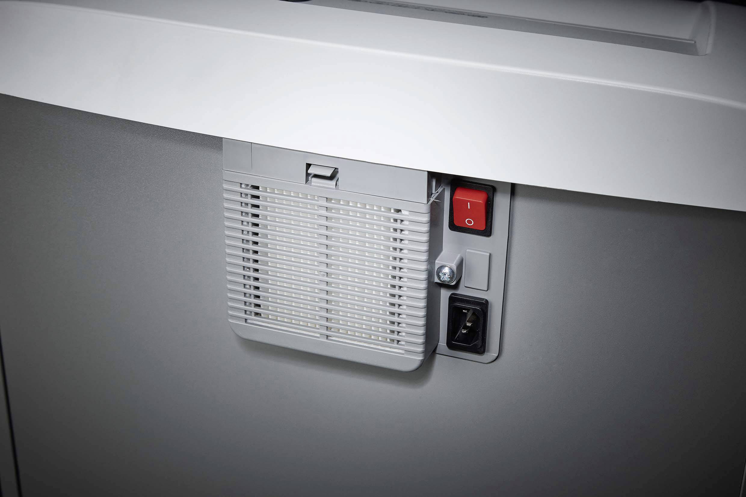 Ein grauer Schredder mit einem Lüftungsgitter vorne. Oben rechts befindet sich ein roter Ein/Aus-Schalter.