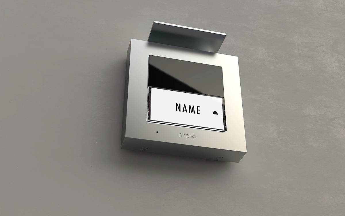 Ein silberner Türsprechanlage mit einem Bildschirm und einem Fach für Beschriftung 'Name'. Die Oberfläche hat ein modernes Design.