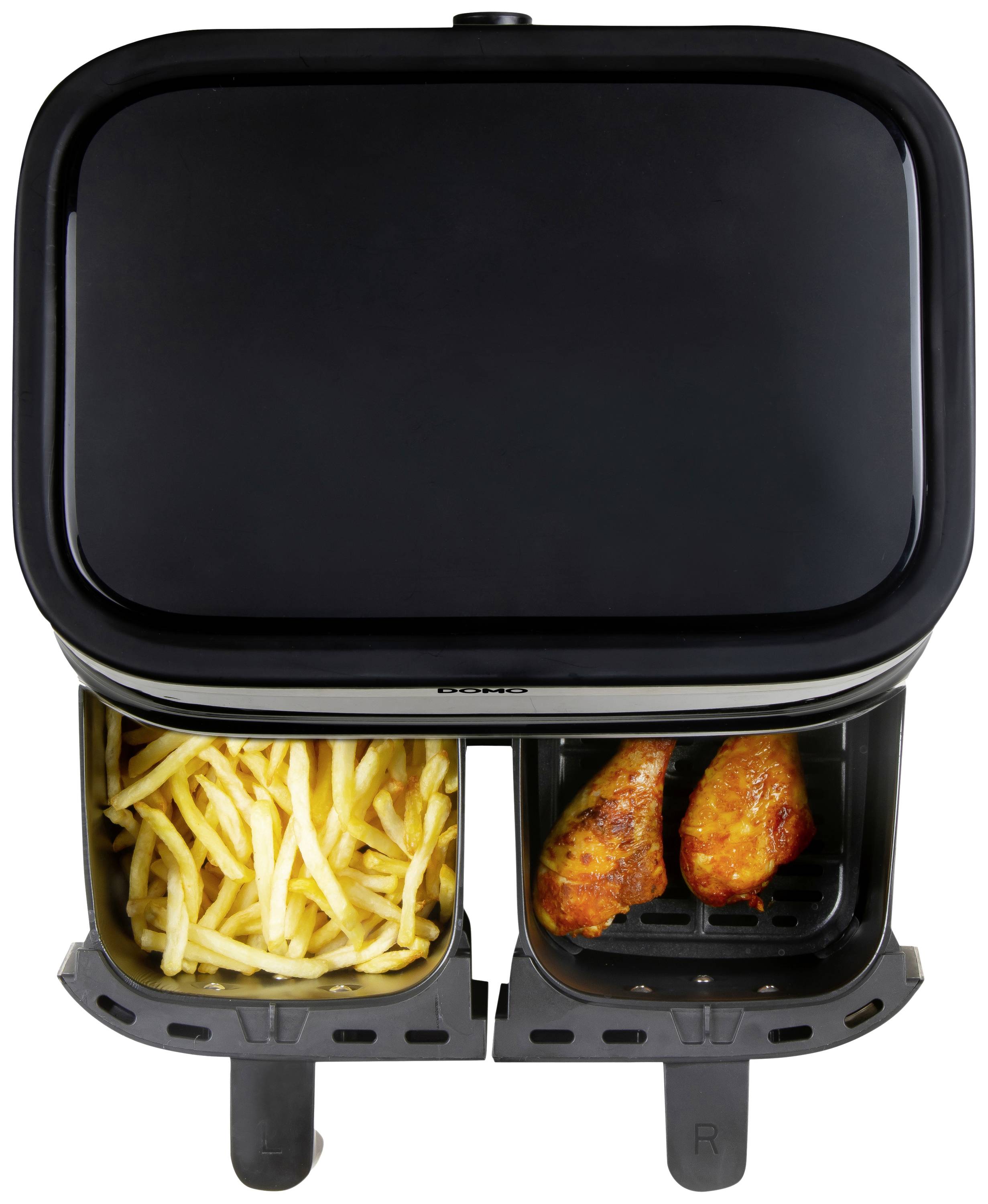 Ein Luftfritteuse mit zwei Fächern, in einem Fach Pommes frites, im anderen zwei Stücke gebratenes Hähnchen.