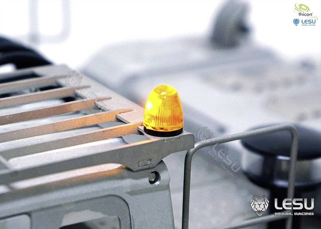 Ein gelbes Warnlicht leuchtet auf einer grauen Metalloberfläche, die Teil einer industriellen Maschine ist. Markenlogos sind sichtbar.