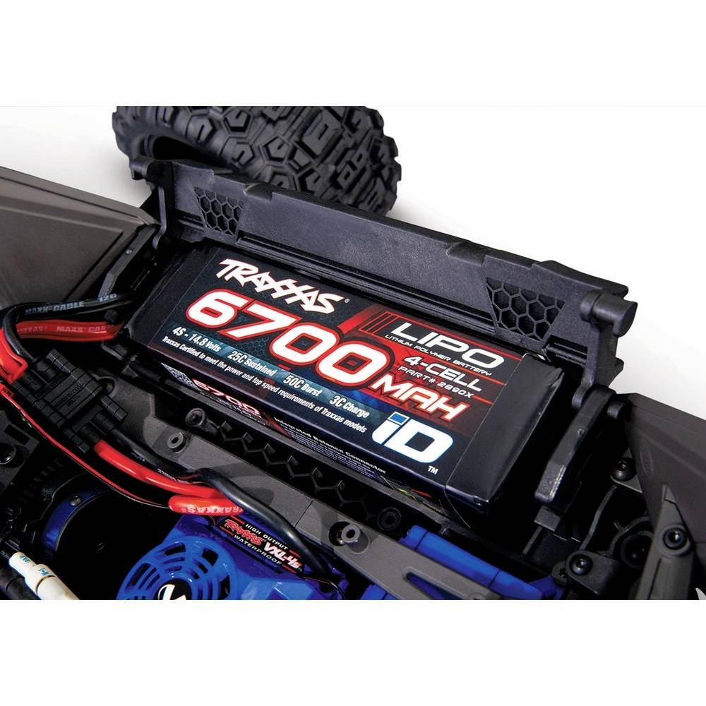 Nahaufnahme eines ferngesteuerten Autos zeigt einen LiPo-Akku mit der Aufschrift '6700 mAh 4-Cell'. Technische Komponenten sind sichtbar.