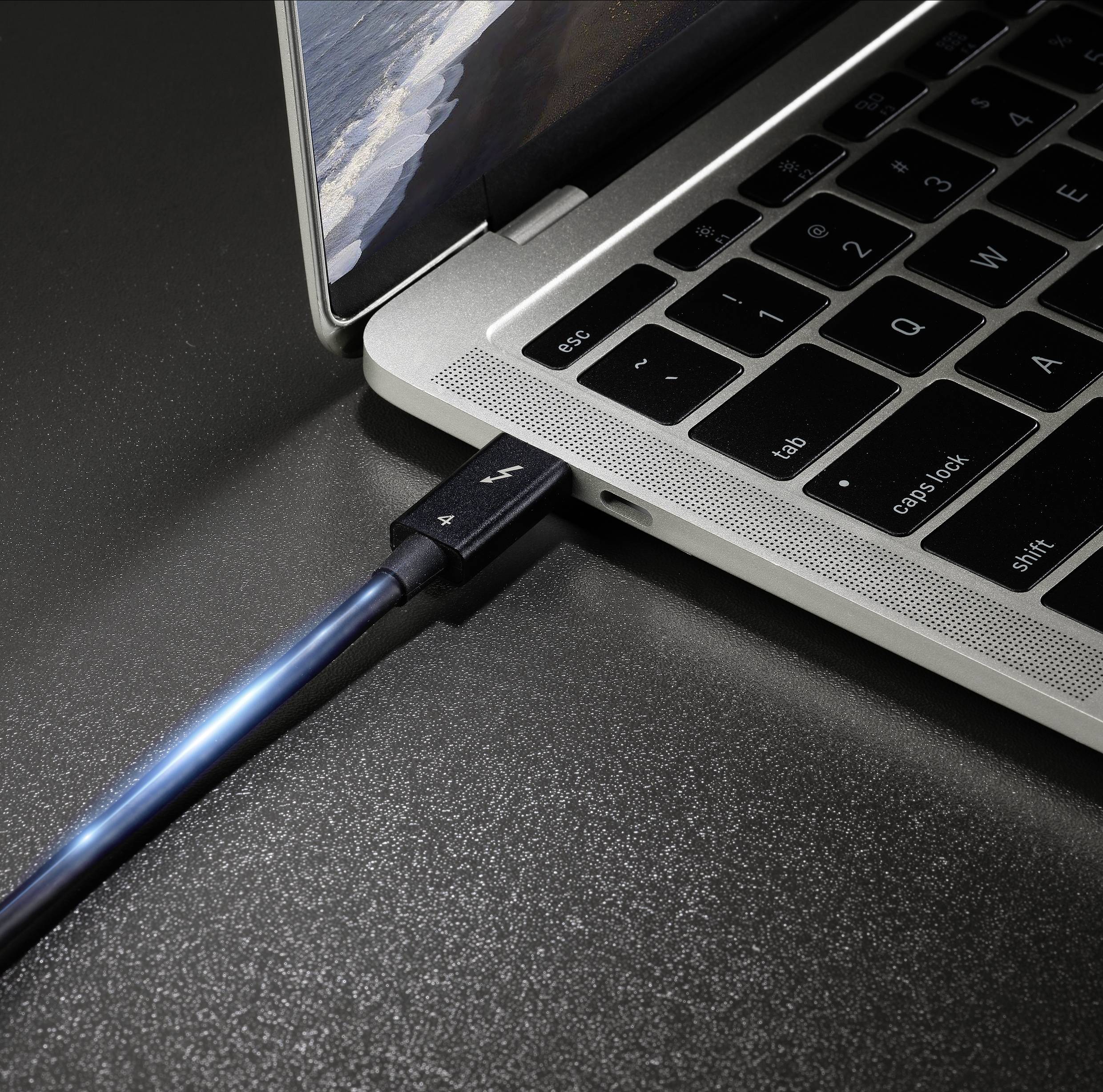 Ein blaues USB-Kabel ist an einen Laptop angeschlossen. Der Laptop zeigt einen Teil des Bildschirms und der Tastatur in Nahaufnahme.