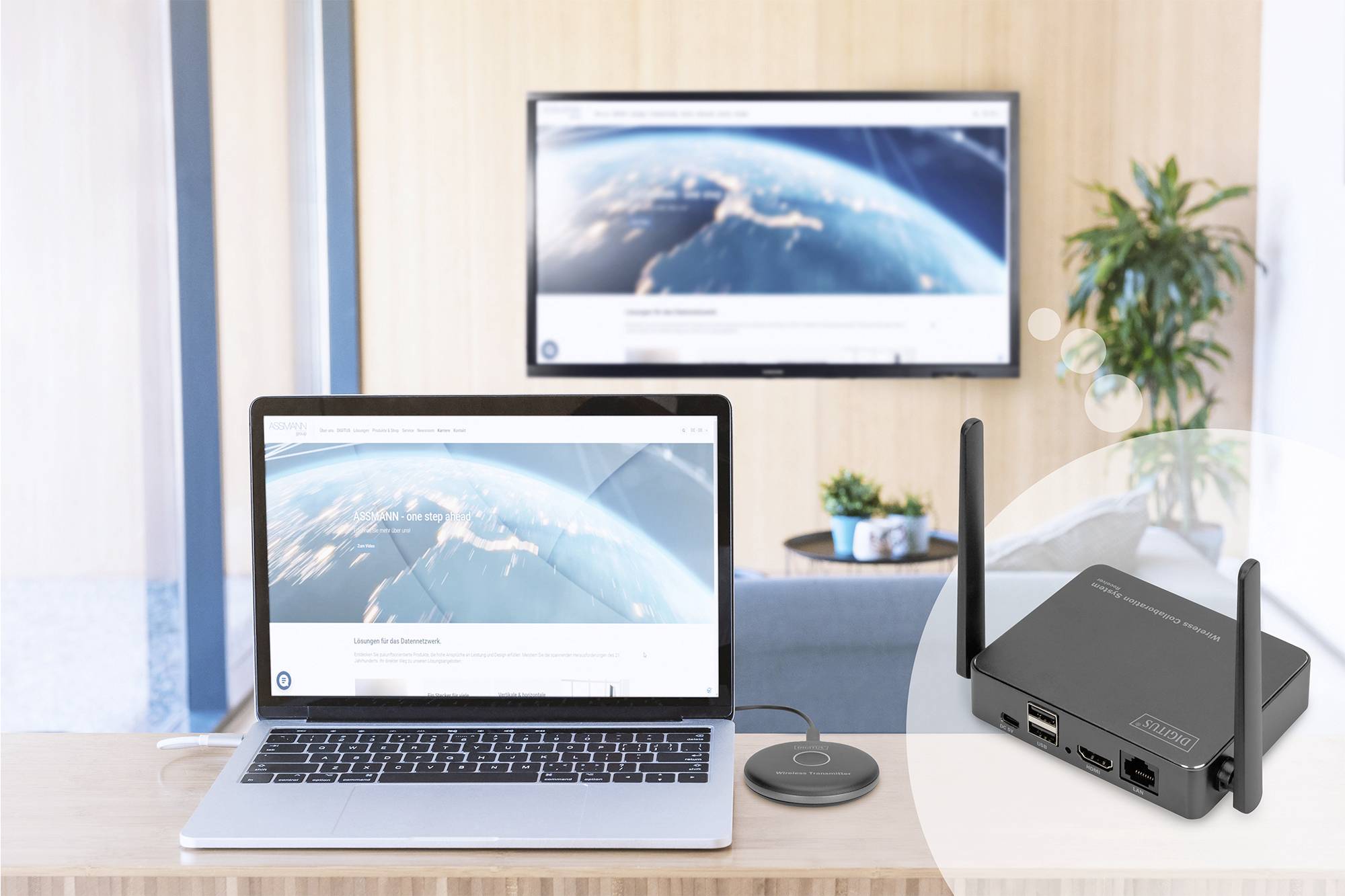 Laptop auf Tisch zeigt Weltkarte, verbindet drahtlos mit angezeigtem Fernseher im Hintergrund. Im Vordergrund WLAN-Gerät und Empfänger.