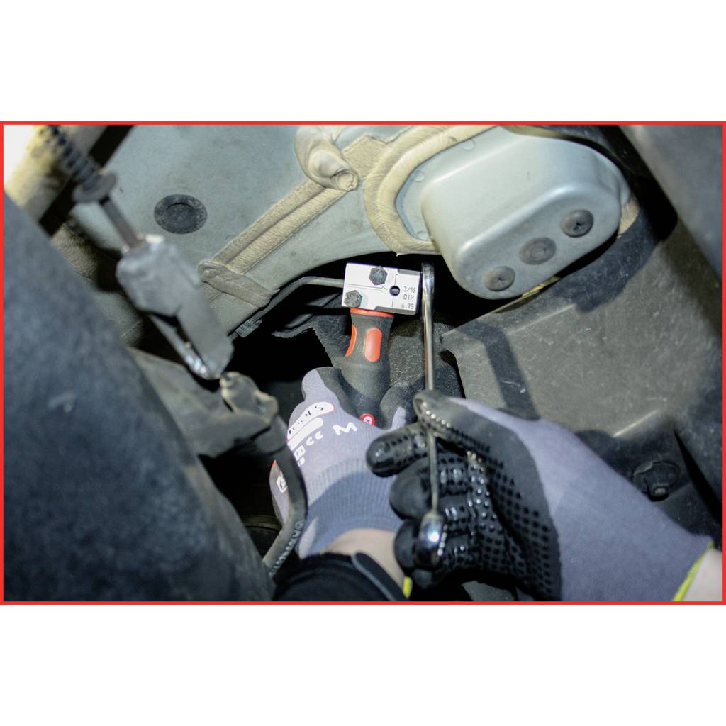 Eine Person zieht mit einer Hand einen Hebel in einem Fahrzeug. Sie trägt Handschuhe und führt Wartungs- oder Reparaturarbeiten durch.