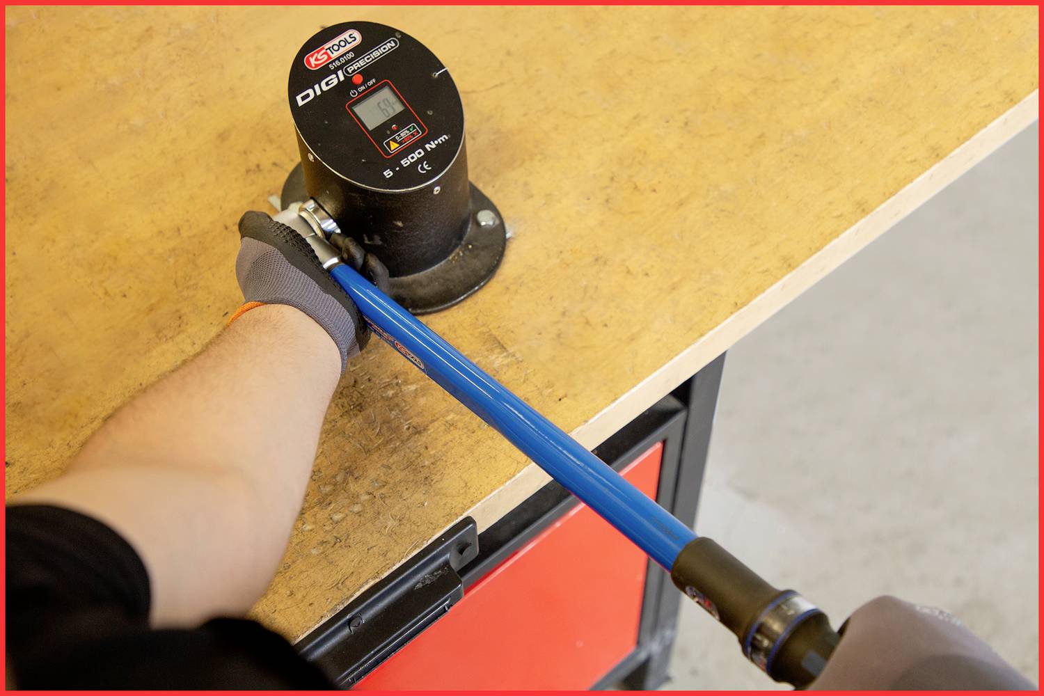 Eine Person verwendet einen Drehmomentschlüssel auf einer Werkbank. Ein digitales Messgerät zeigt den momentanen Drehmomentwert an.