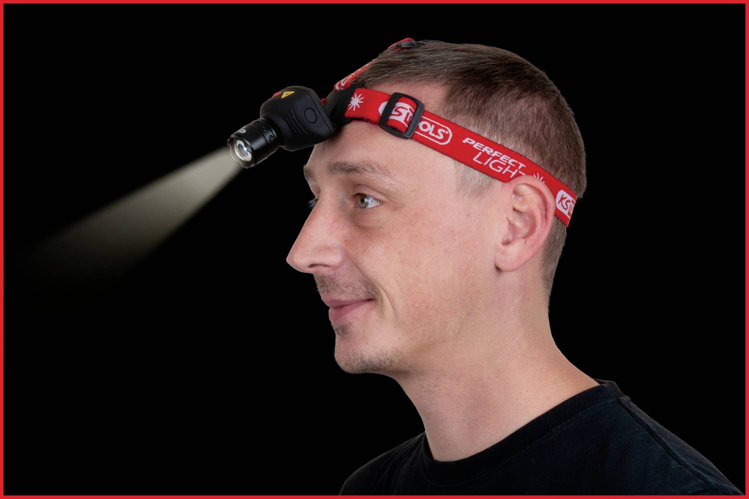 Ein Mann trägt eine Stirnlampe, die eingeschaltet ist und nach vorne leuchtet. Er blickt zur Seite und trägt ein schwarzes T-Shirt.