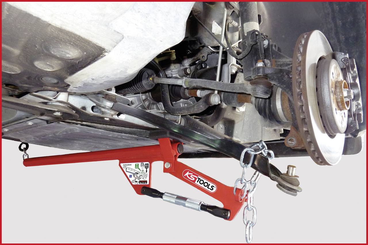 Fahrzeug aufgebockt, mit Radaufhängung sichtbar. Ein rotes Werkzeug stabilisiert das Radlagergehäuse auf der rechten Seite.